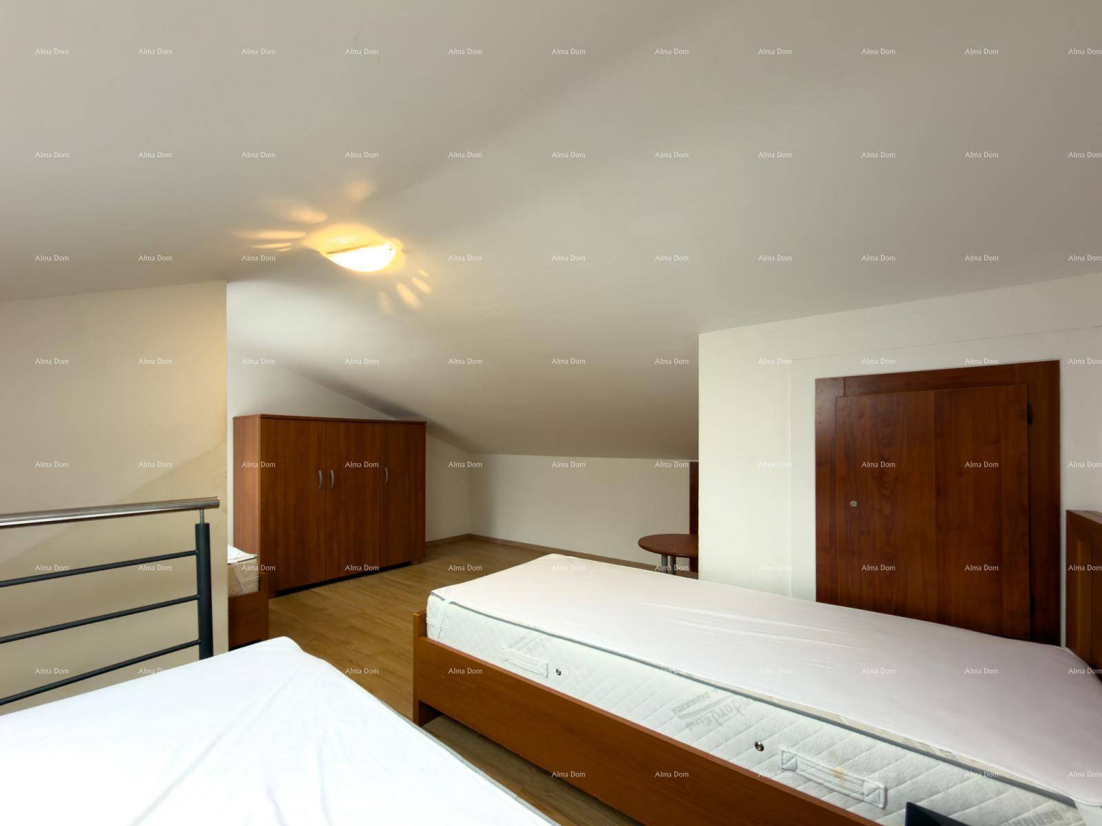 Dachgeschoss-Schlafzimmer mit Betten, Kleiderschrank und schrägen Wänden unter dem Dach.