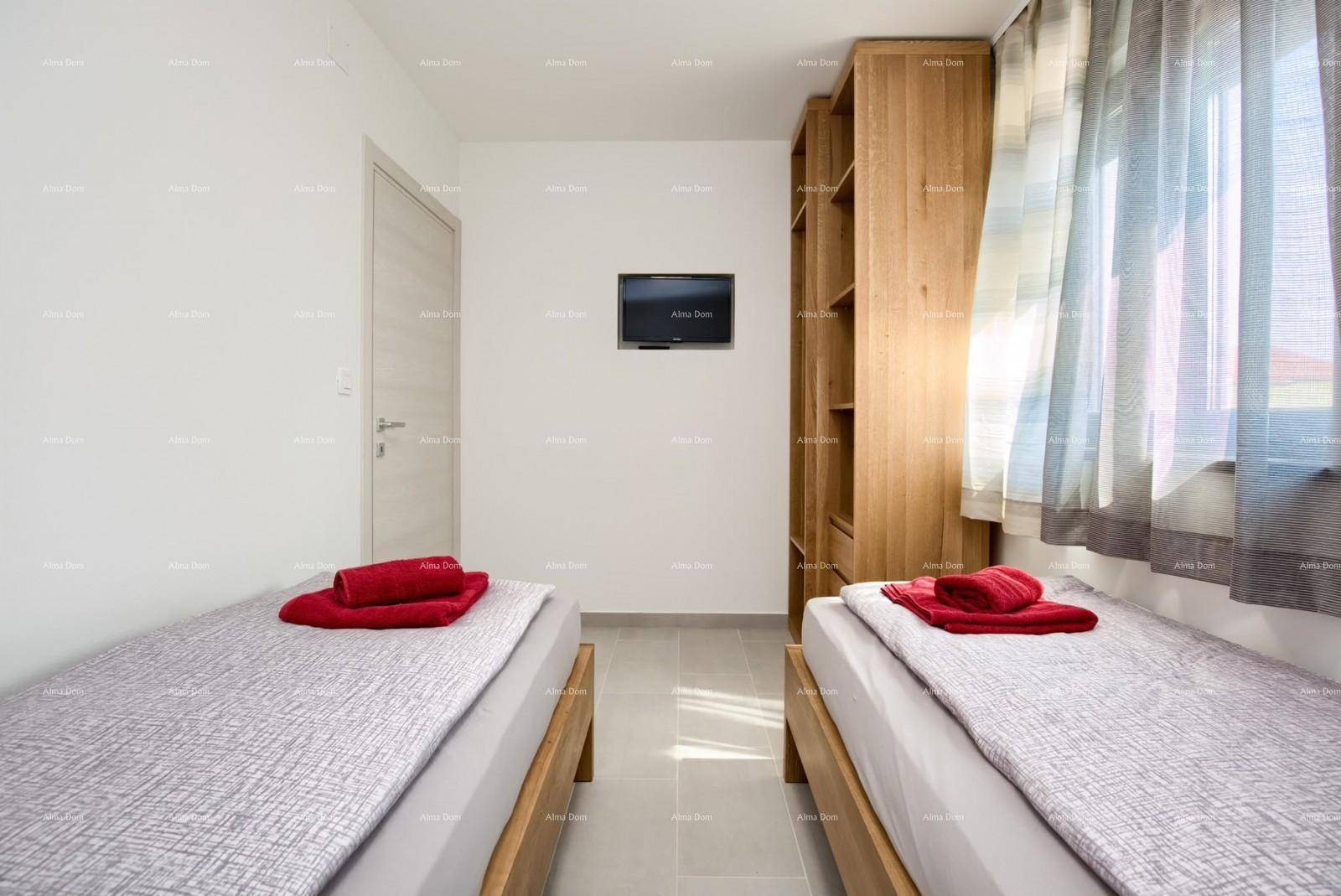 Schlafzimmer mit zwei Einzelbetten, Wandfernseher und offenem Holzregal neben einem Fenster.