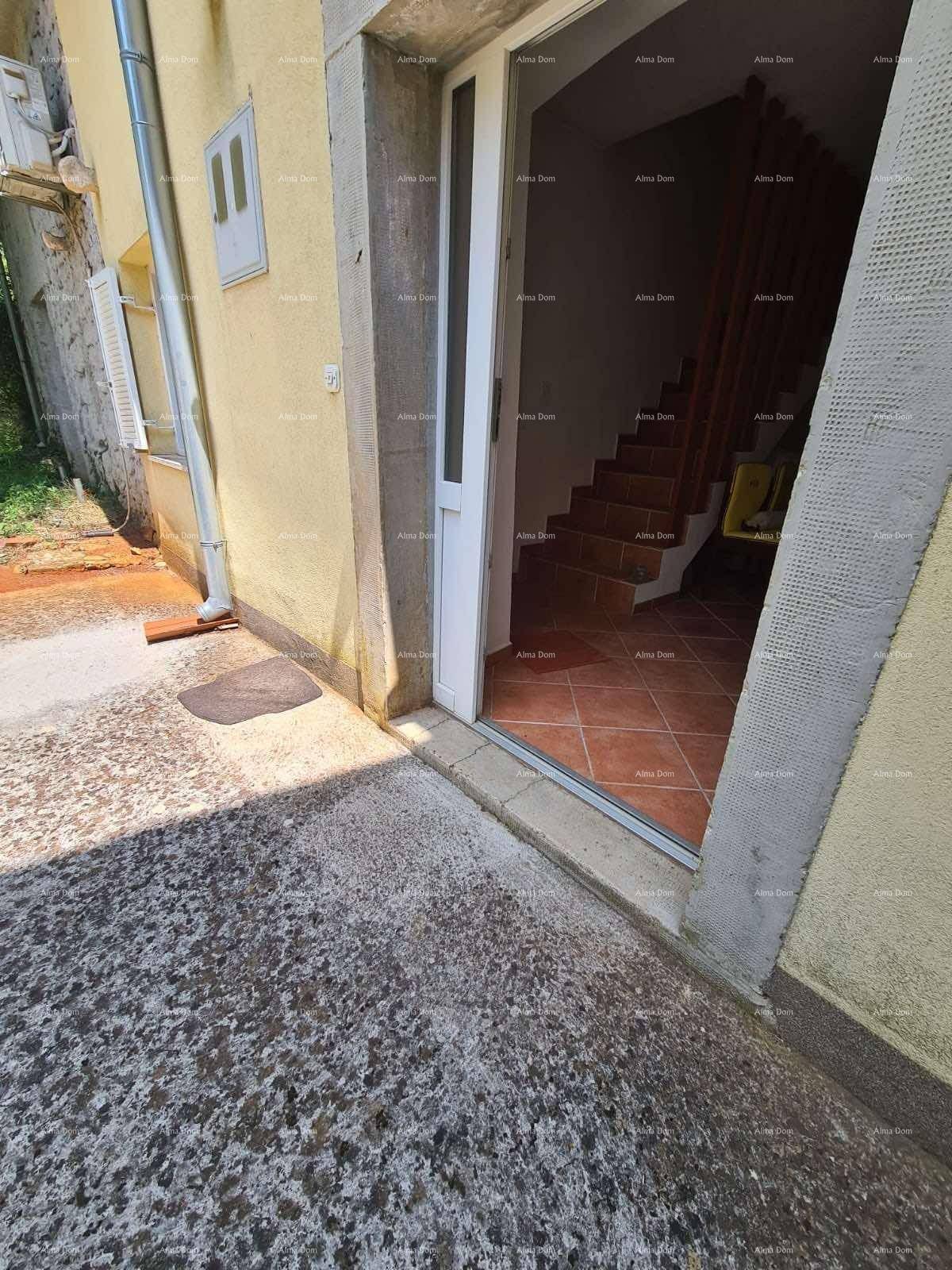 Eingangsbereich des Hauses mit gelber Fassade und offener Tür, die den Blick ins Innere freigibt.