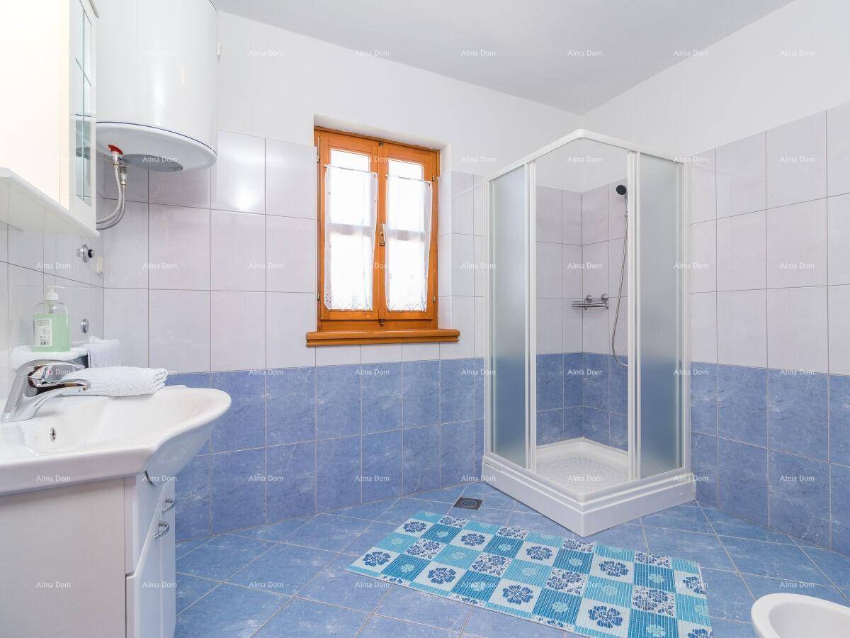 Badezimmer mit blauen und weißen Fliesen, Duschkabine und Fenster.