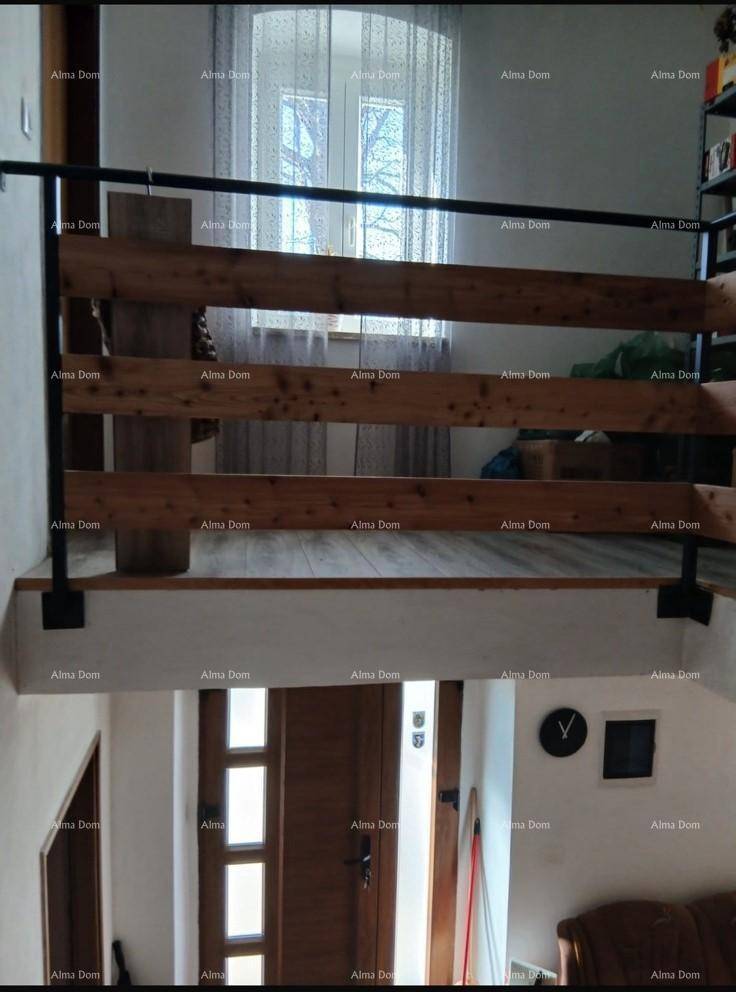 Innenliegende Holztreppe mit Geländer und Fenster, die verschiedene Ebenen des Hauses verbindet.