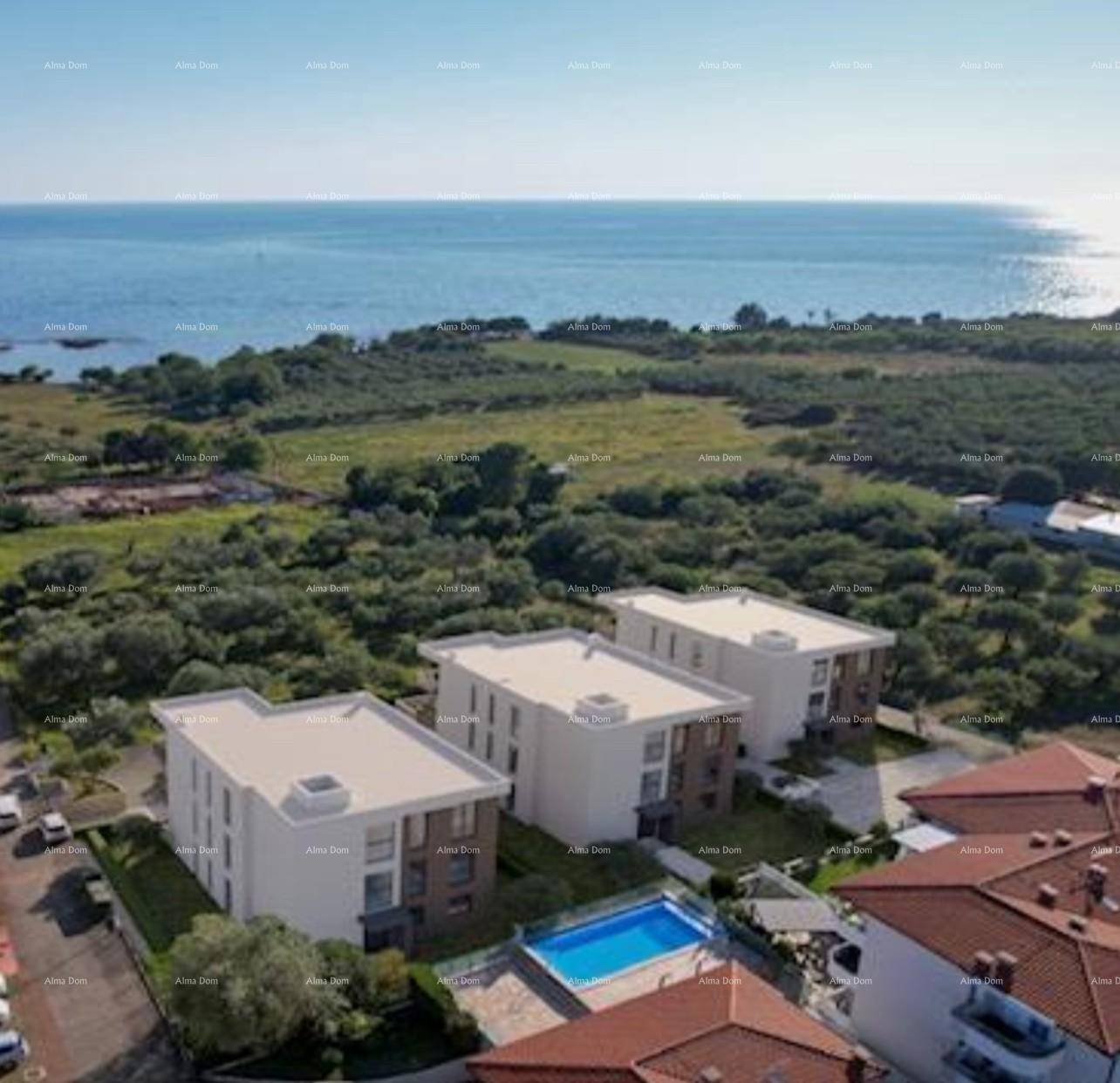 Luftaufnahme von modernen Wohngebäuden mit Pool, umgeben von Grünflächen und Meerblick in der Ferne.