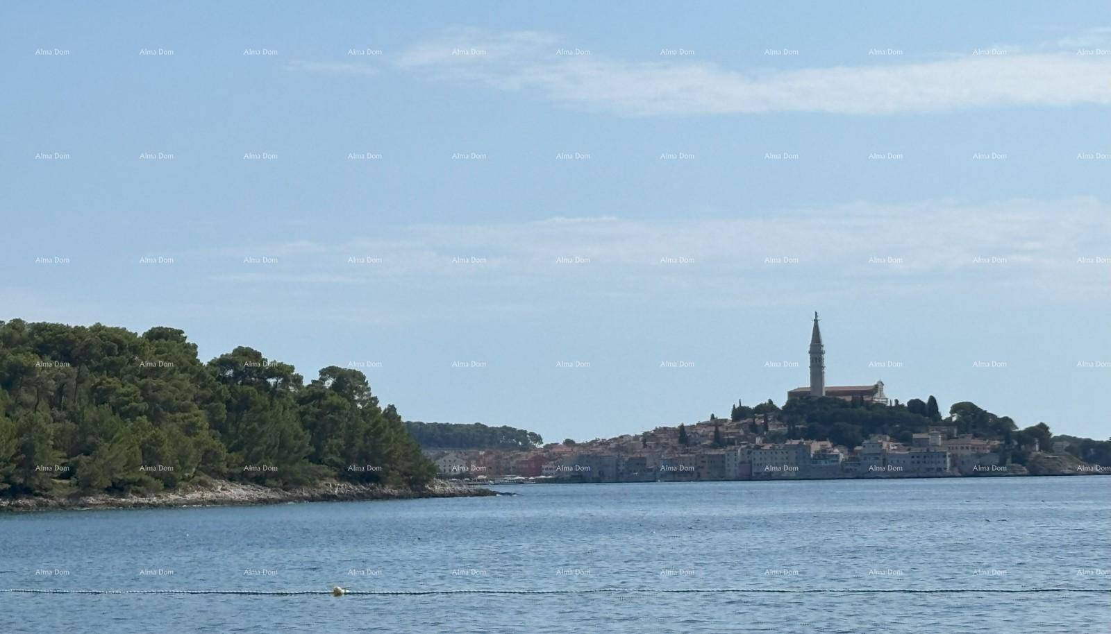 Panoramablick auf eine malerische Küstenstadt mit einem markanten Kirchturm am Horizont.