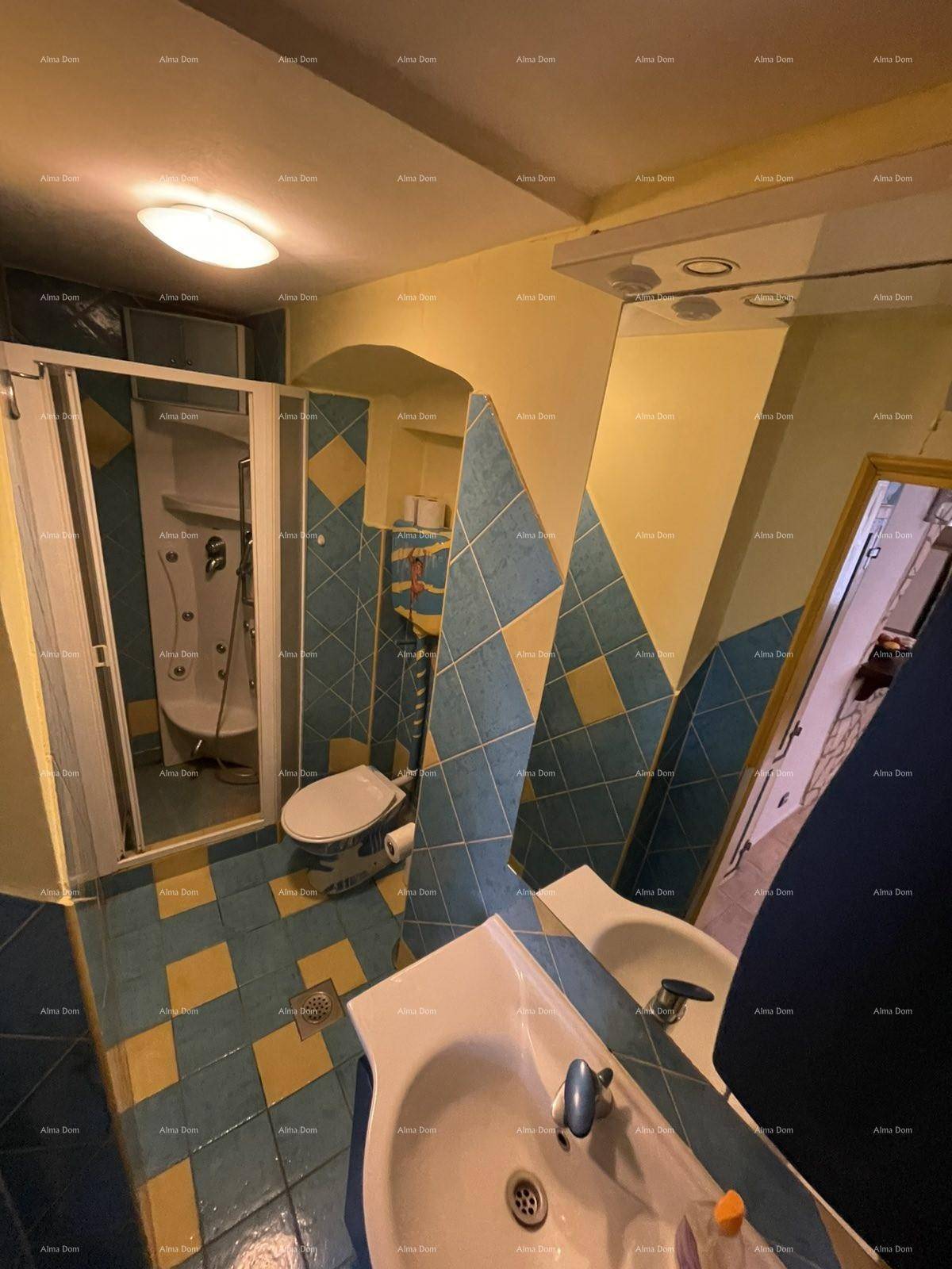 Badezimmer mit auffälligen blau-gelben Fliesen, Duschkabine, Toilette, Waschbecken und Bidet.