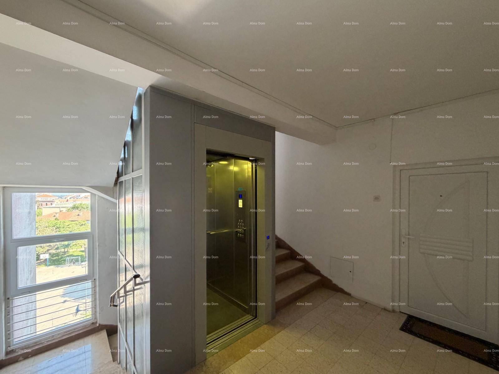 Heller Treppenaufgang mit modernem Aufzug und Fenster mit Blick nach draußen.