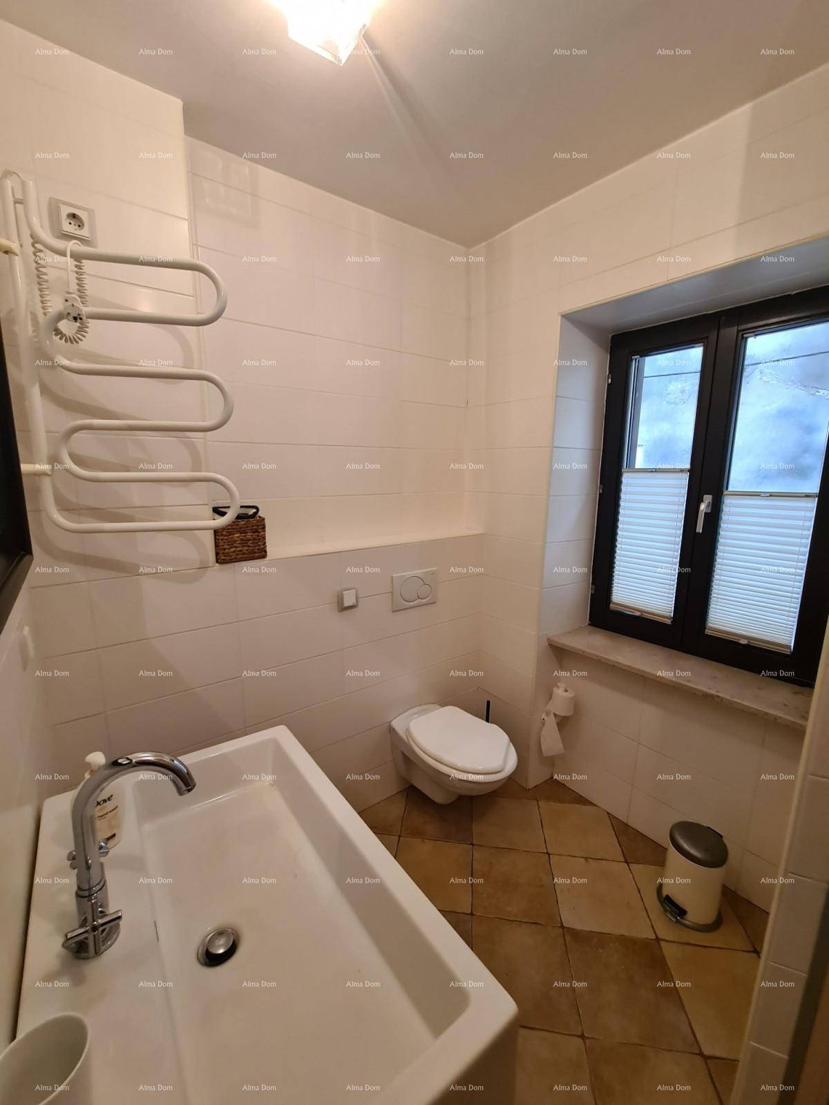 Helles Badezimmer mit WC, Waschbecken, Fenster und praktischem Handtuchheizkörper.