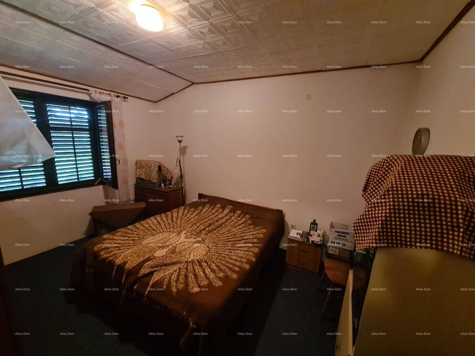 Schlafzimmer mit Doppelbett, dunklem Teppichboden und einem Fenster mit Jalousien für Privatsphäre.