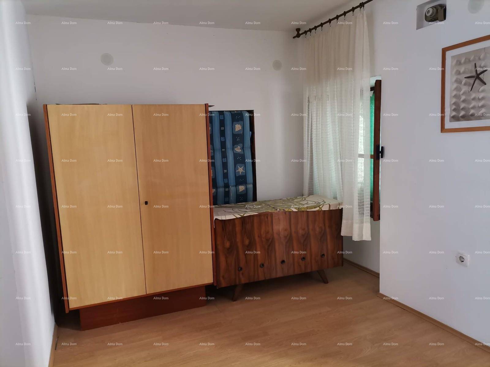 Schlafzimmer mit Kleiderschrank, Kinderbett und Fenster mit Vorhängen.