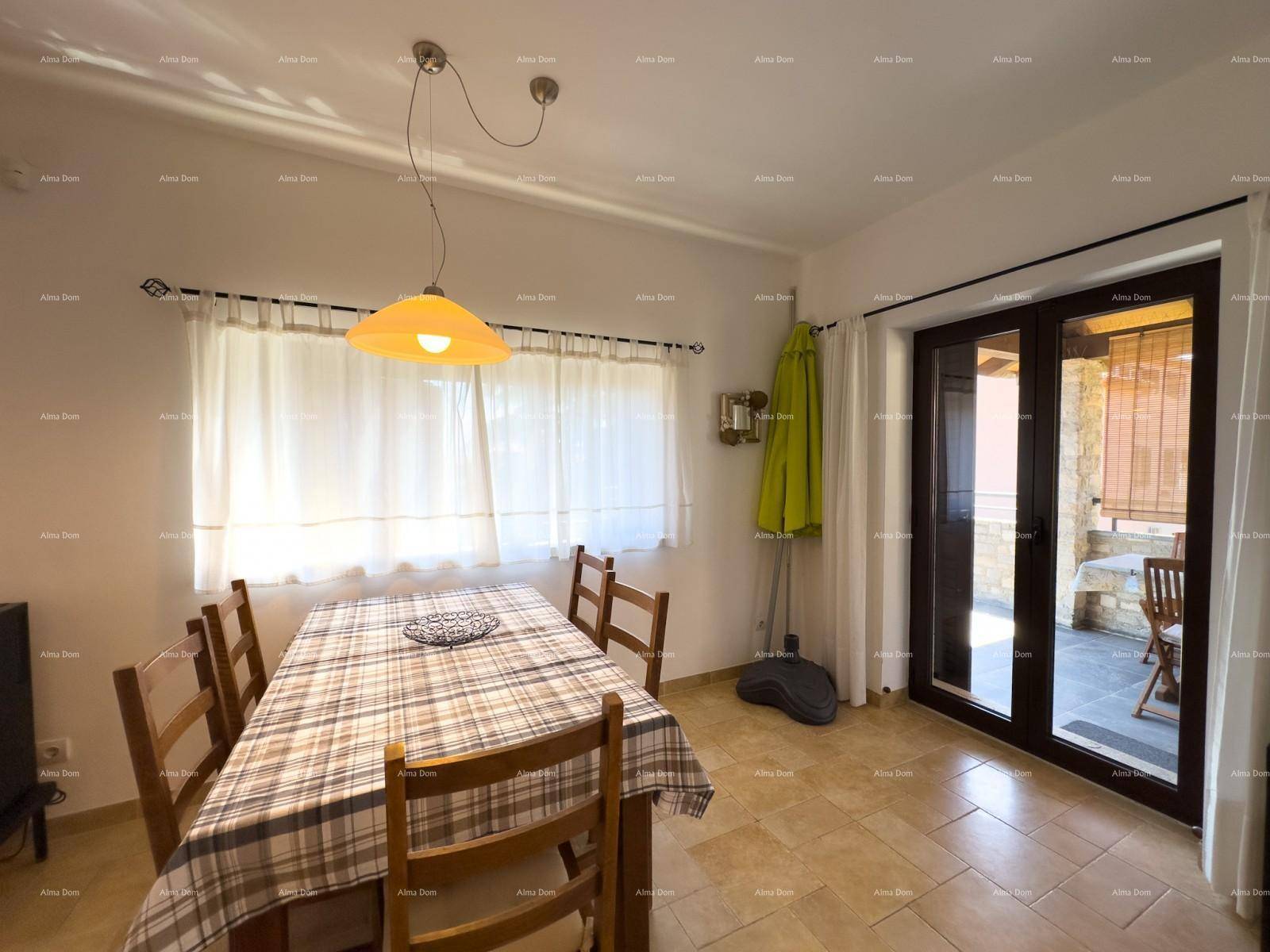 Heller Essbereich mit karierter Tischdecke, Fliesenboden und Zugang zur überdachten Terrasse.