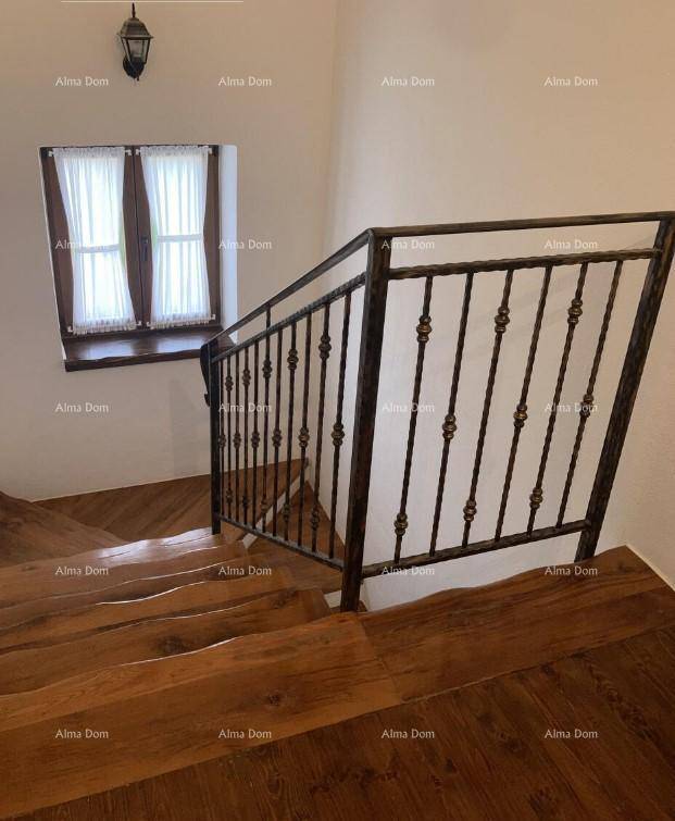 Elegante Holztreppe mit schmiedeeisernem Geländer und einem Fenster, das natürliches Licht hereinlässt.