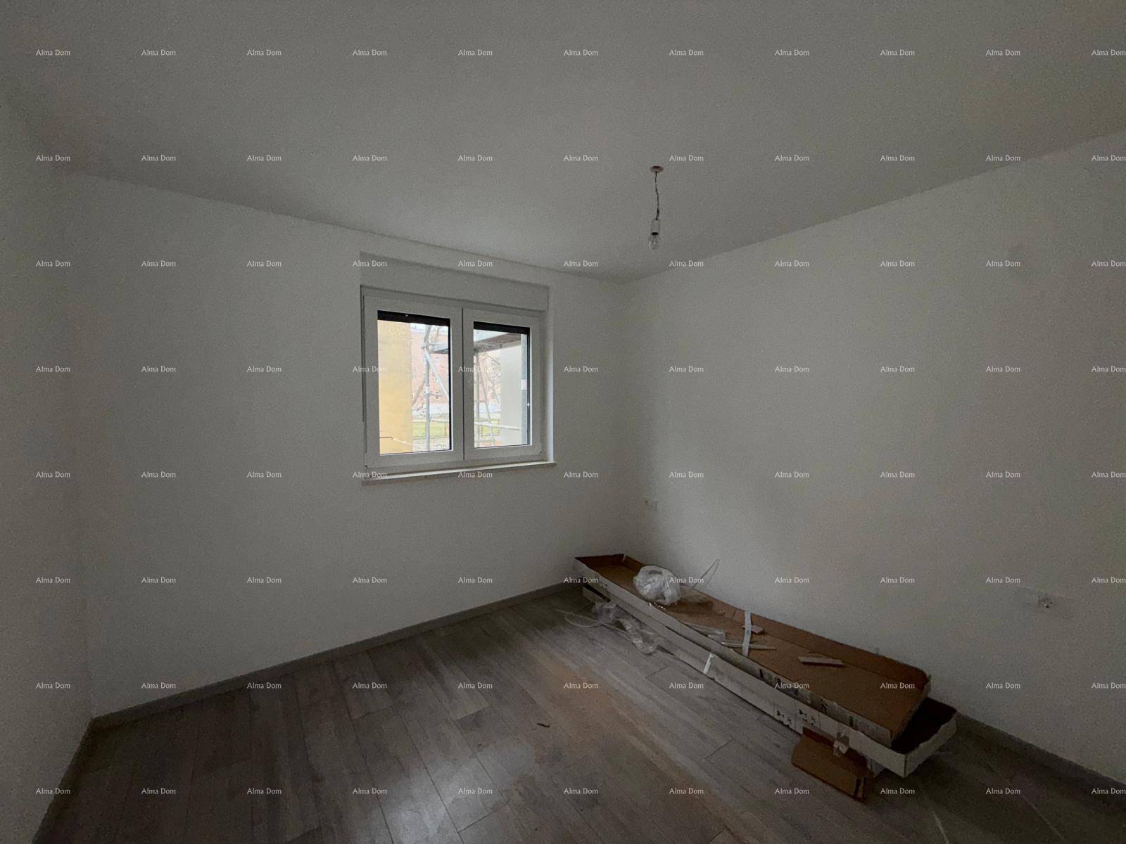 Leeres Schlafzimmer mit Holzboden und einem Fenster, das den Blick nach draußen freigibt.