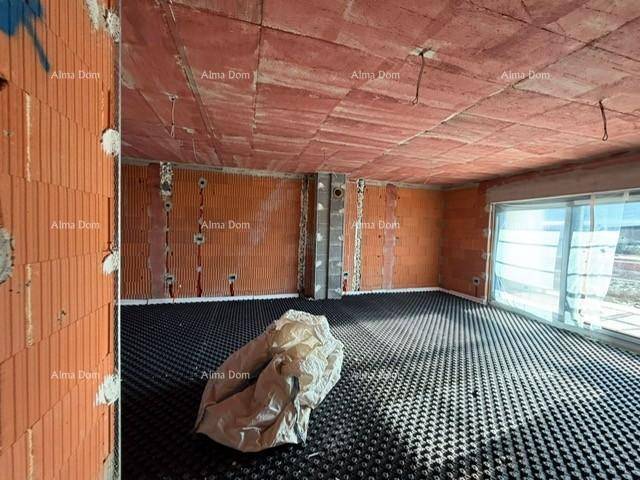 Geräumiger unfertiger Wohnraum mit Ziegelwänden und Fußbodenheizungsvorbereitung für zukünftigen Komfort.