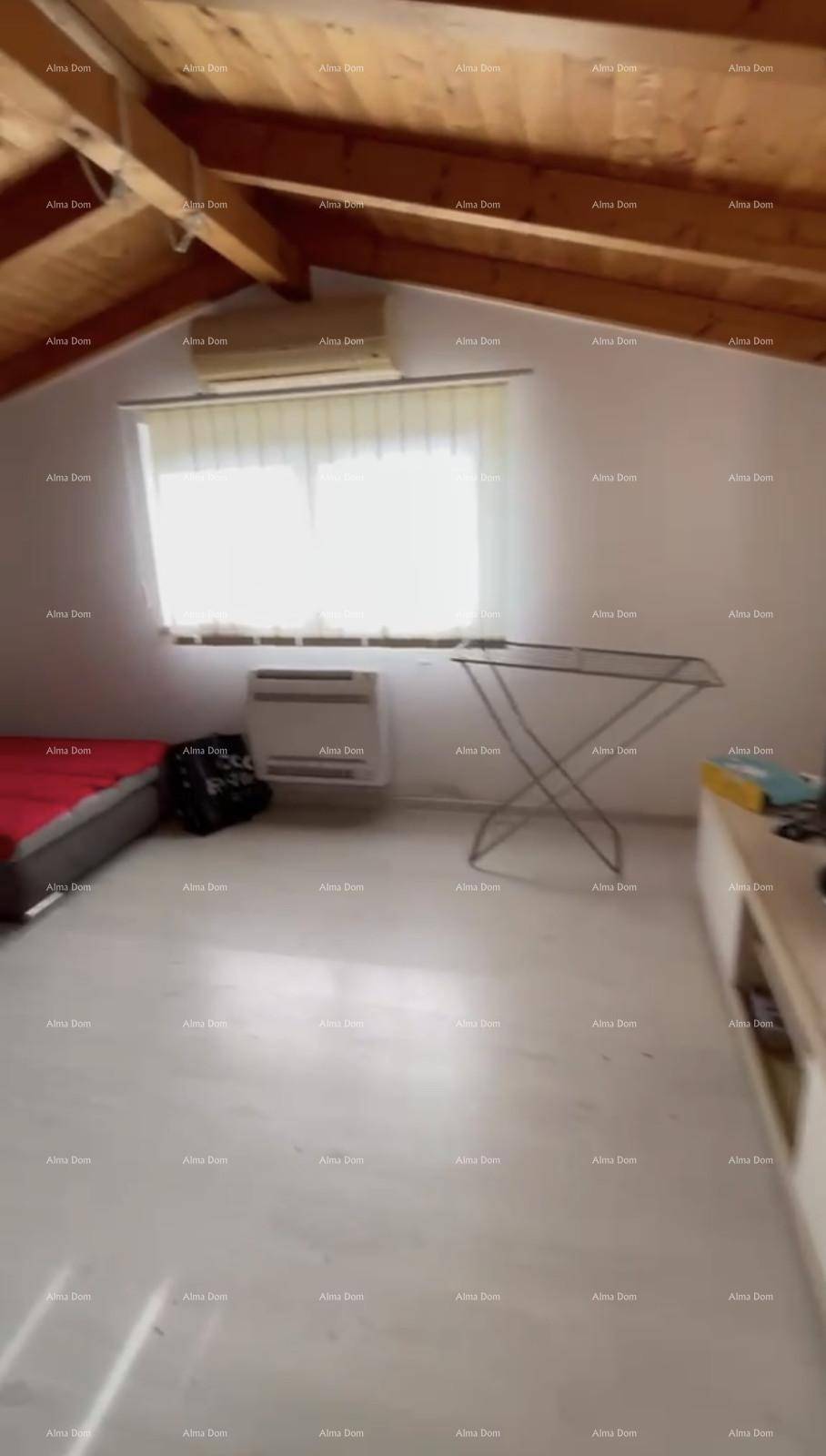 Helles Zimmer mit Schlafsofa, Klimaanlage, Fenster und schräger Holzdachkonstruktion.