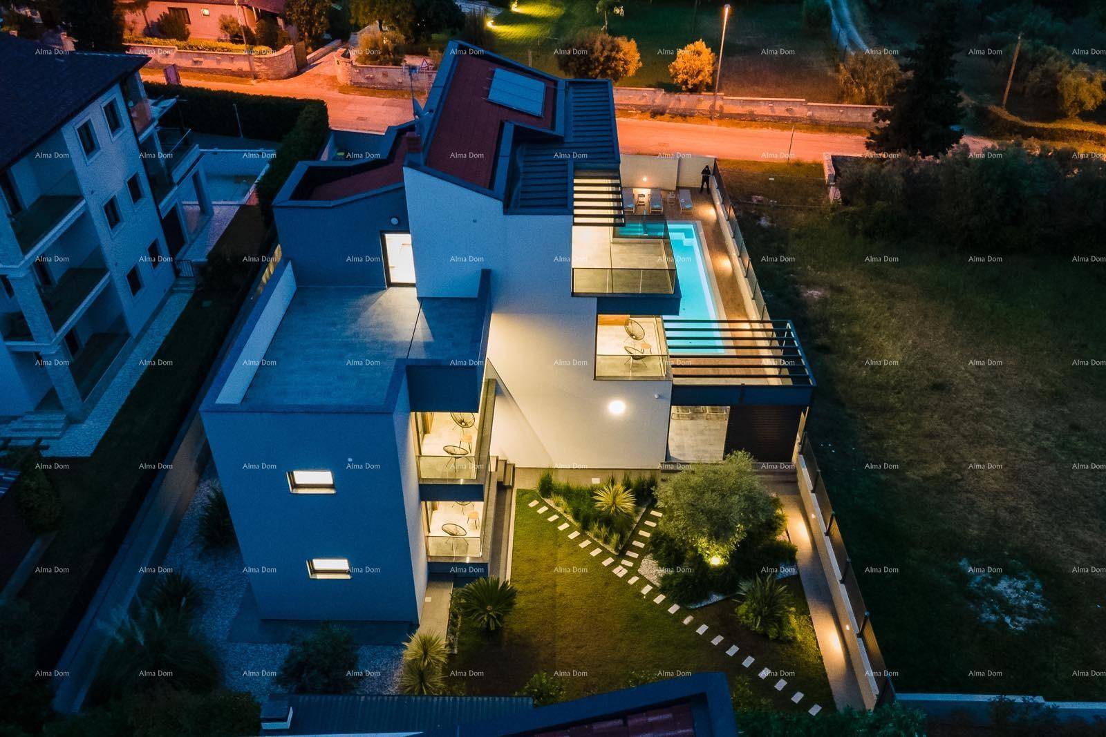 Luftaufnahme der modernen Villa bei Nacht mit beleuchtetem Pool und Gartenanlage.
