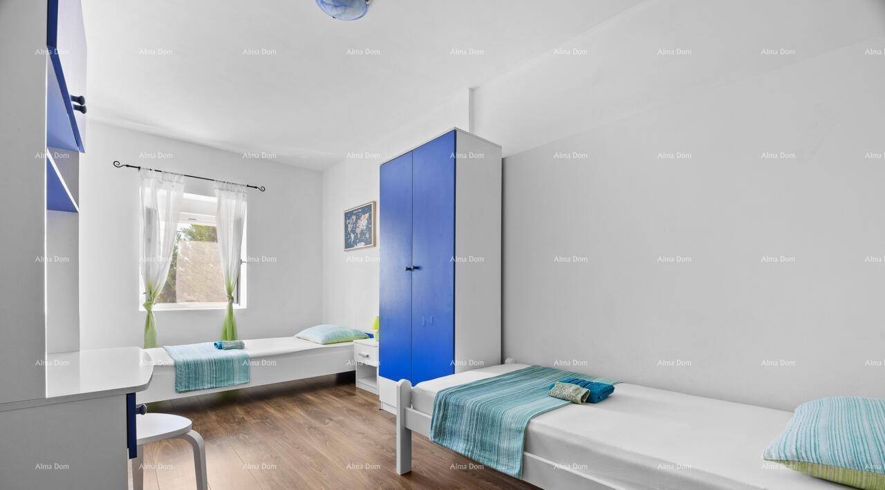 Helles Schlafzimmer mit zwei Einzelbetten, blauem Kleiderschrank und einem Schreibtisch.