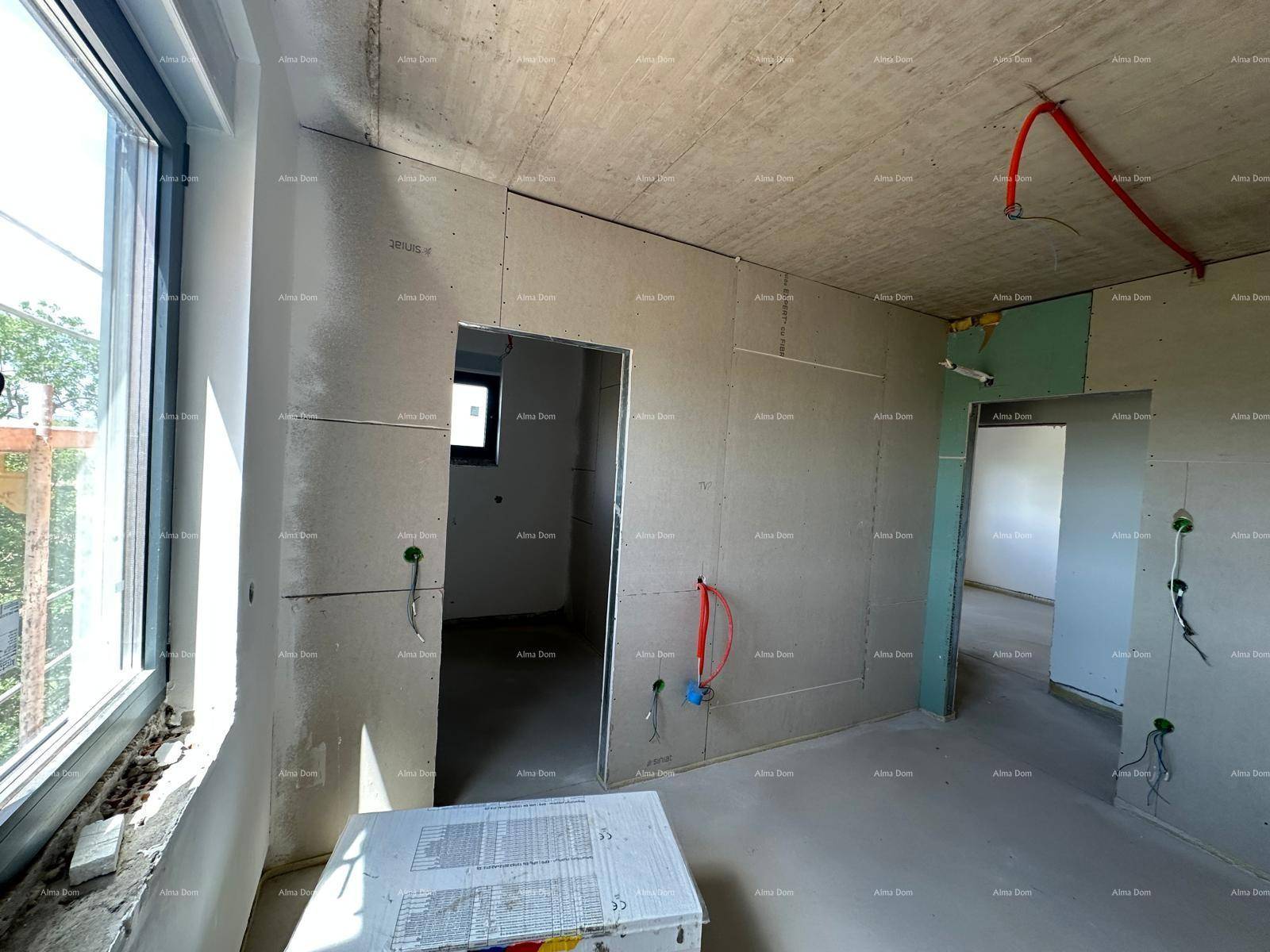 Geräumiger Wohnbereich im Rohbau mit großen Fenstern, Blick ins Grüne und vorbereiteten Installationen.