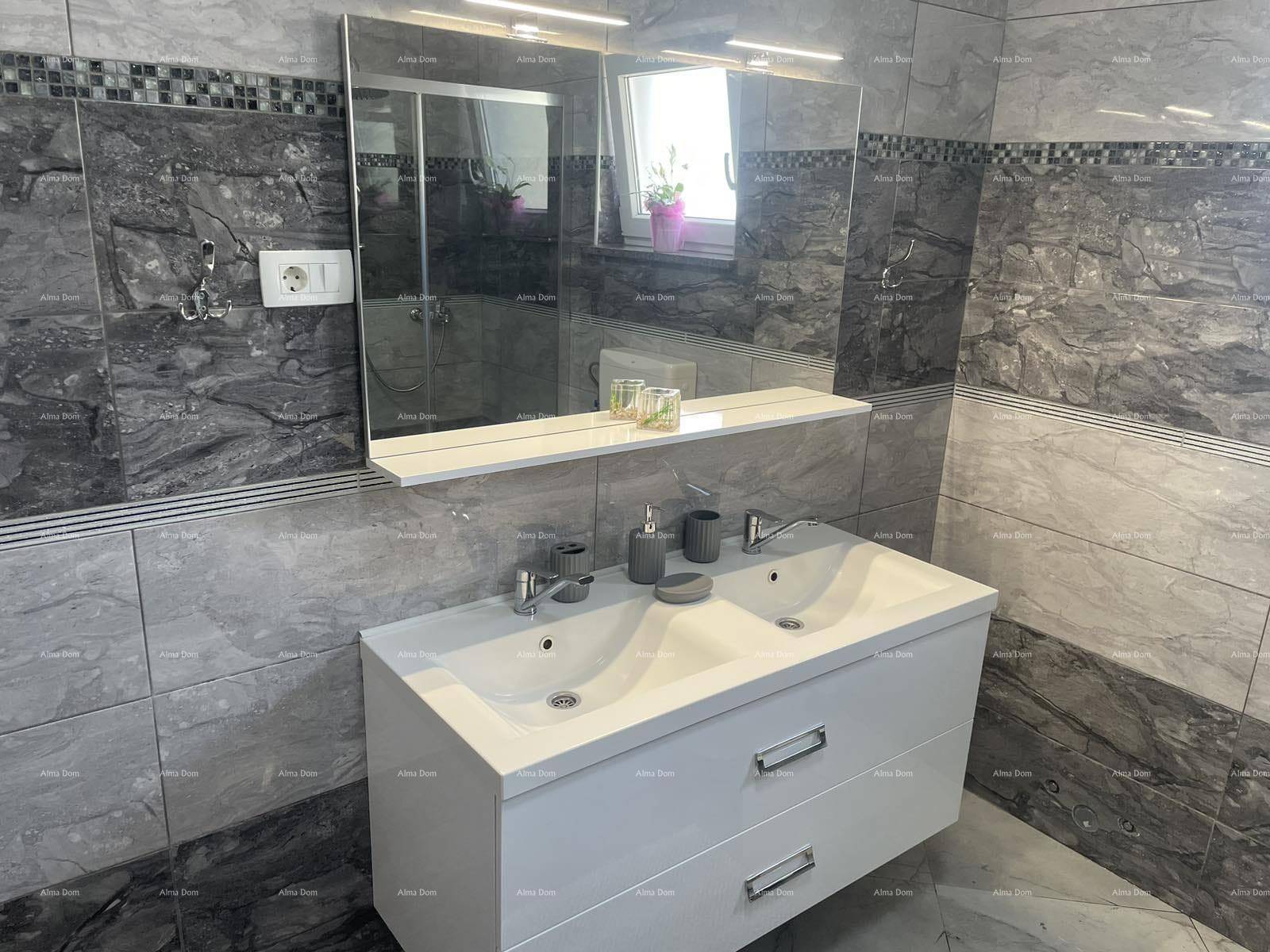 Modernes Badezimmer mit Doppelwaschbecken, großem Spiegel und stilvollen grauen Fliesen.