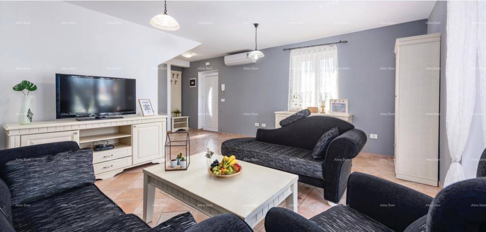Gemütliches Wohnzimmer mit grauen Wänden, dunklen Sofas und einem Fernseher auf einem Sideboard.