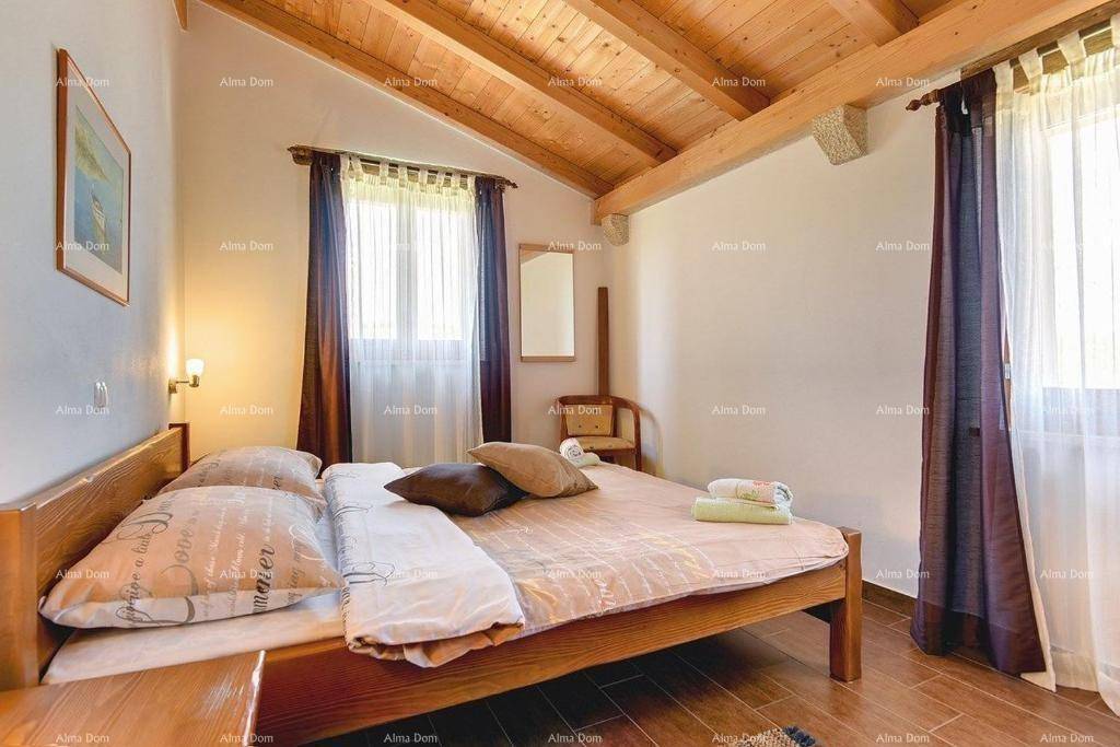 Schlafzimmer mit Holzbalkendecke, Doppelbett und Fenster mit Vorhängen.
