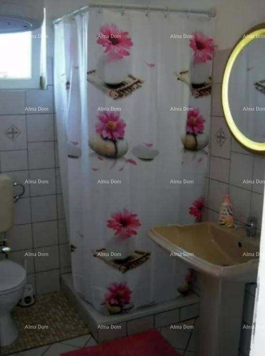 Kleines Badezimmer mit Duschkabine, WC und Waschbecken, hell gefliest.