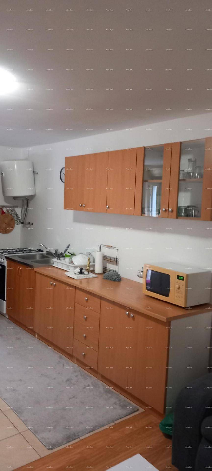 Funktionale Küche mit Holzschränken, Spüle, Herd und einer freistehenden Mikrowelle.