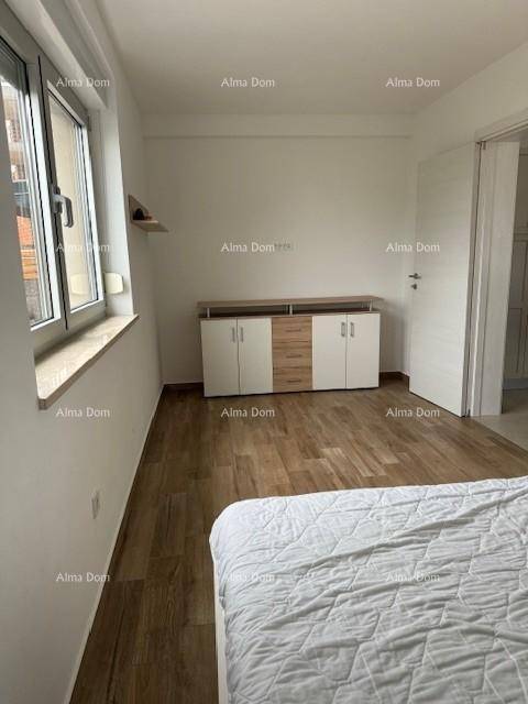 Schlafzimmer mit Holzfußboden, einem modernen Sideboard und großen Fenstern.