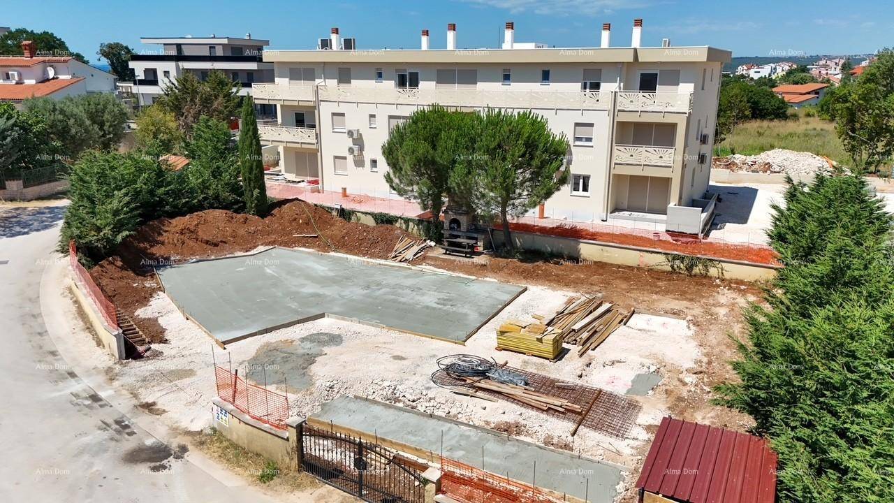 Mehrstöckiges Wohngebäude mit heller Fassade und einer Baustelle im Vordergrund unter blauem Himmel.