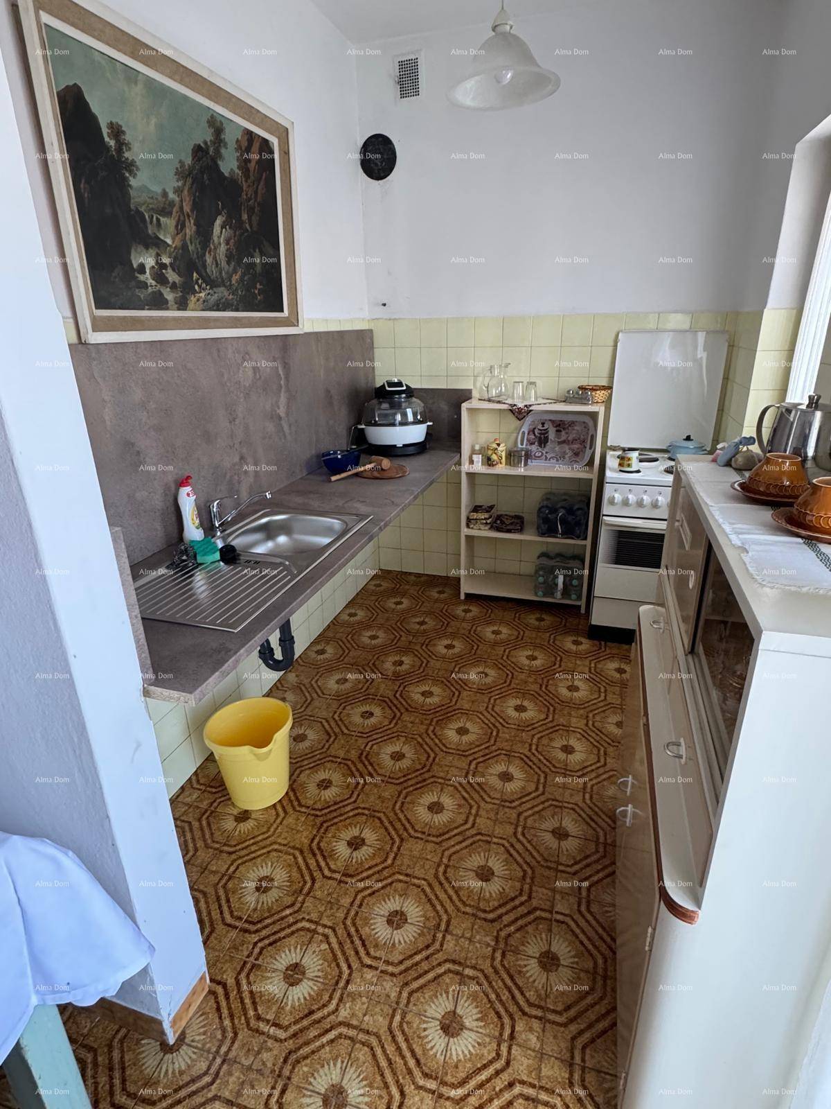 Einfache Küche mit Spüle, Herd und Kühlschrank, ausgestattet mit gemusterten Fliesen.