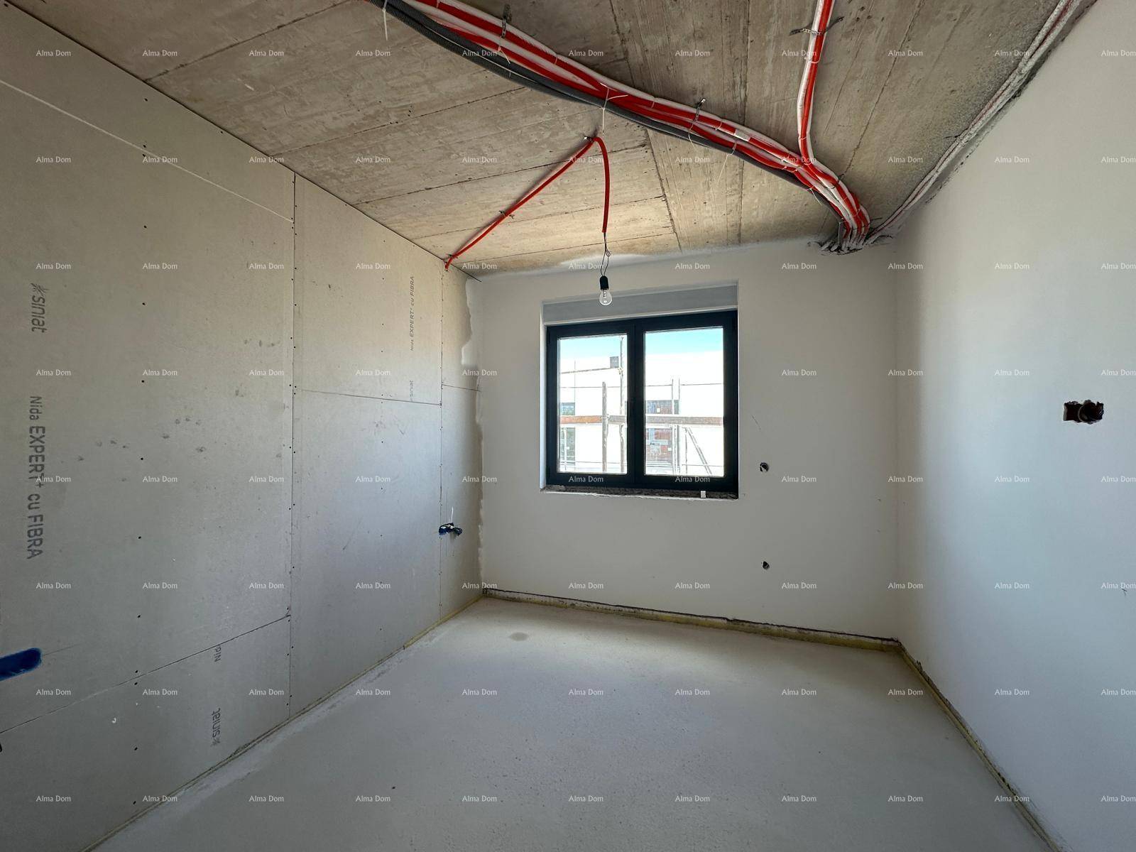 Schlafzimmer im Rohbau mit Trockenbauwänden, sichtbaren Deckenleitungen und einem Fenster.