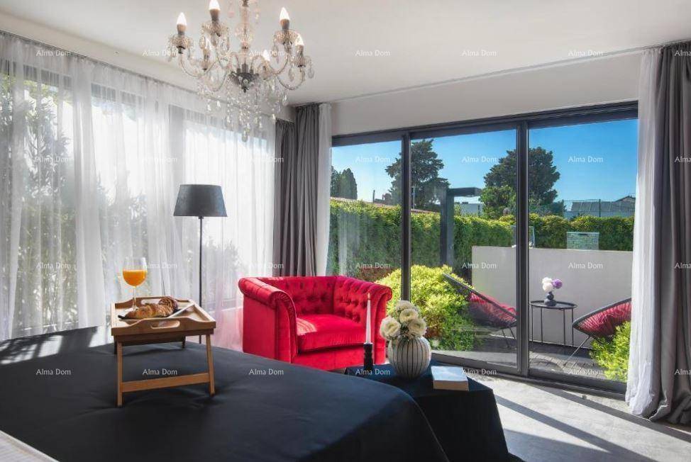 Helles Schlafzimmer mit großem Fenster, rotem Sessel und Kronleuchter, bietet direkten Zugang zum Garten.