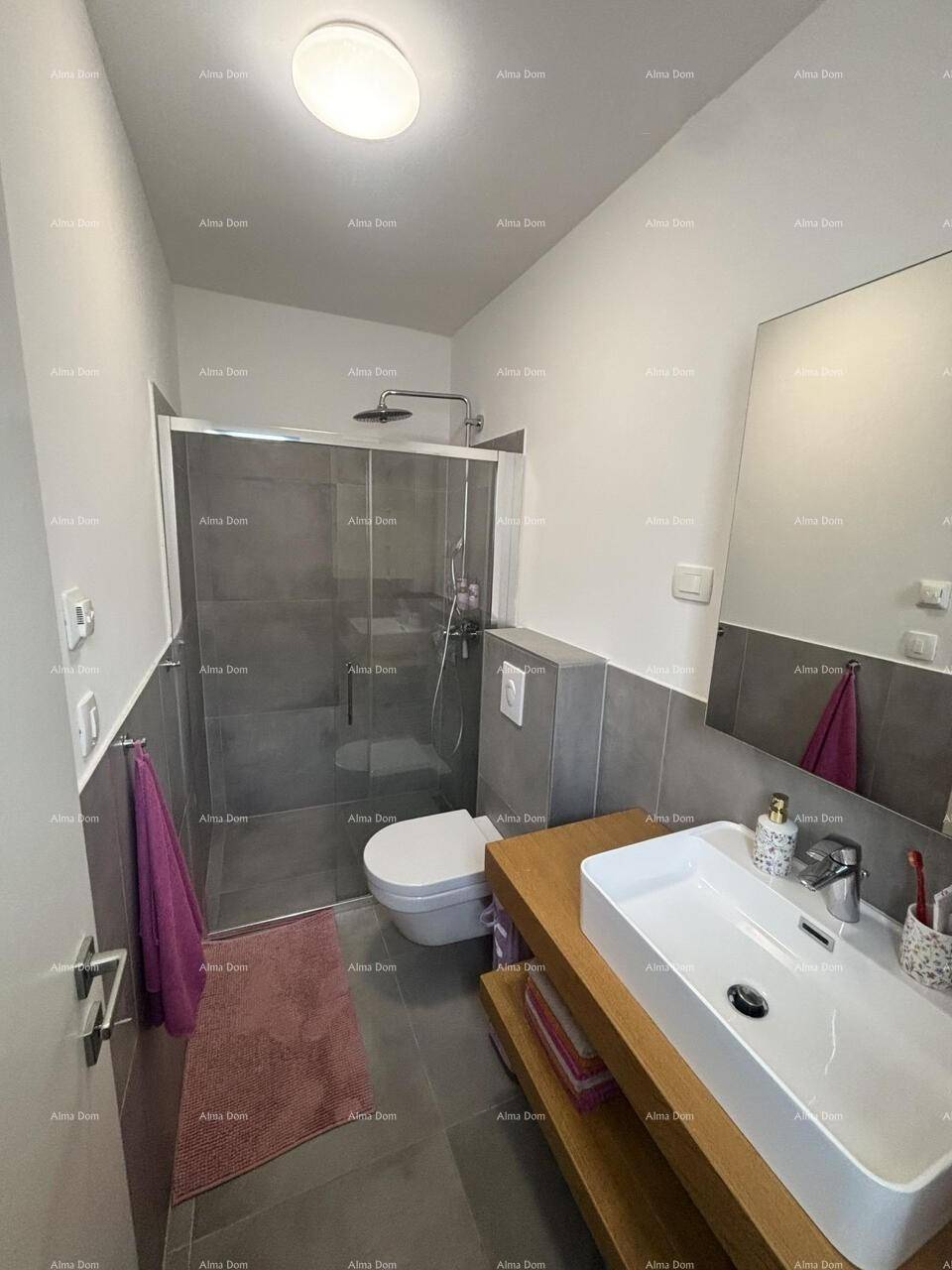 Modernes Badezimmer mit begehbarer Dusche, Einzelwaschbecken und grauen Fliesen.