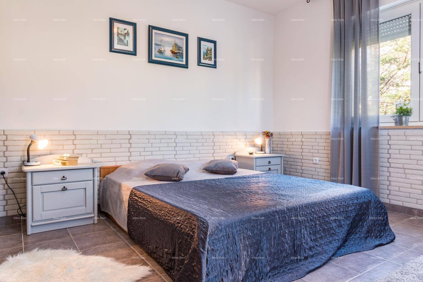Schlafzimmer mit Doppelbett, Nachttischen und großem Fenster mit Vorhängen.