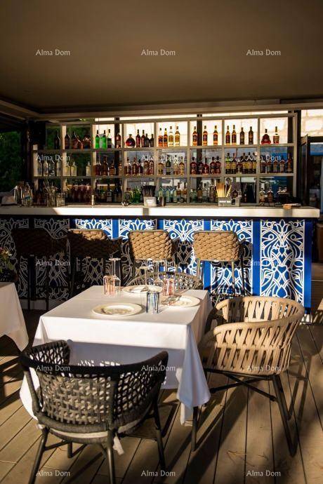 Innenbereich einer Bar mit reich gefüllten Regalen und einem Tisch mit geflochtenen Stühlen.