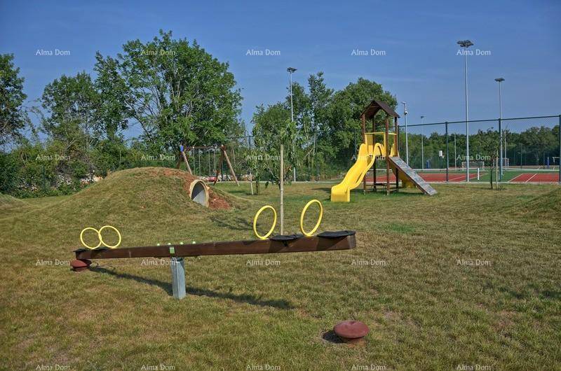 Kinderspielplatz mit Rutsche, Wippe und Schaukeln neben Sportfeldern.