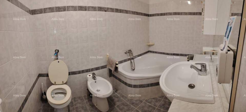 Badezimmer mit Eckbadewanne, Toilette, Bidet und Waschbecken, komplett gefliest in hellen Tönen.