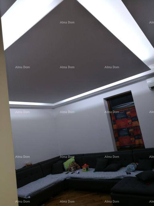 Geräumiges Wohnzimmer mit indirekter Deckenbeleuchtung, großem Ecksofa und Klimaanlage.