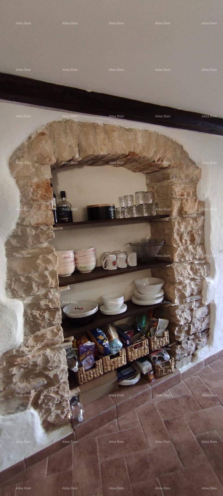 Rustikale Steinwandnische mit Holzregalen, gefüllt mit Geschirr und Vorräten, auf Terrakotta-Fliesenboden.