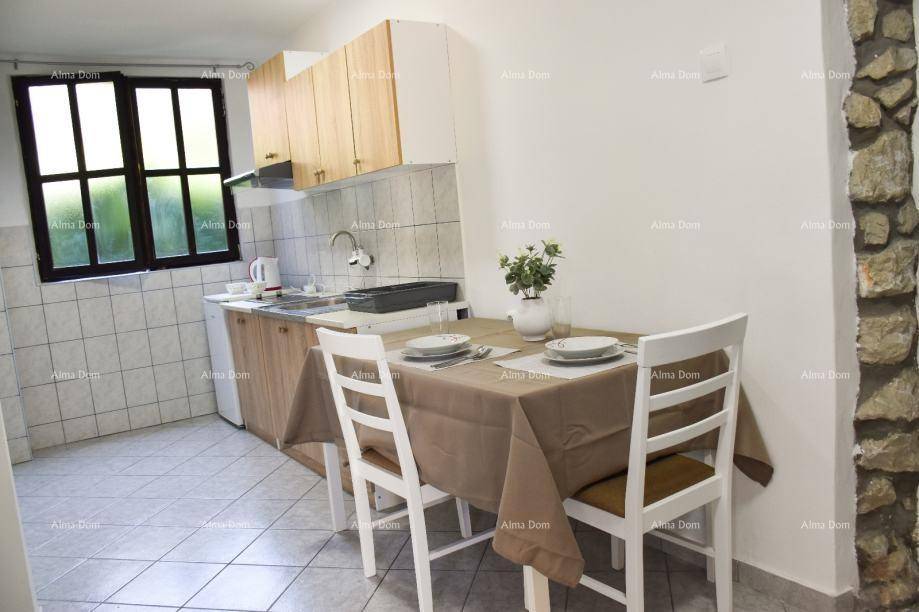 Gemütliche Küche mit Esstisch, Spüle und einem Fenster, ergänzt durch eine Steinwand.