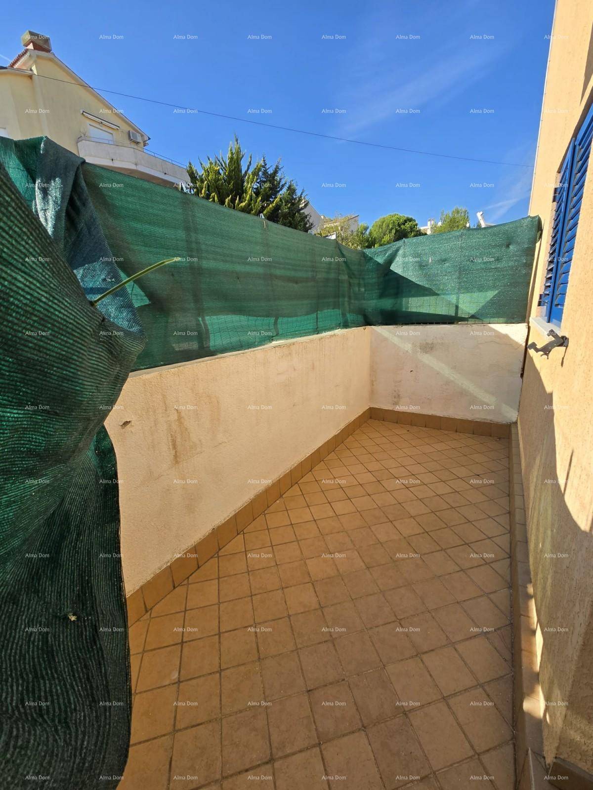 Kleine, private Terrasse mit Fliesenboden und grüner Sichtschutzabgrenzung.
