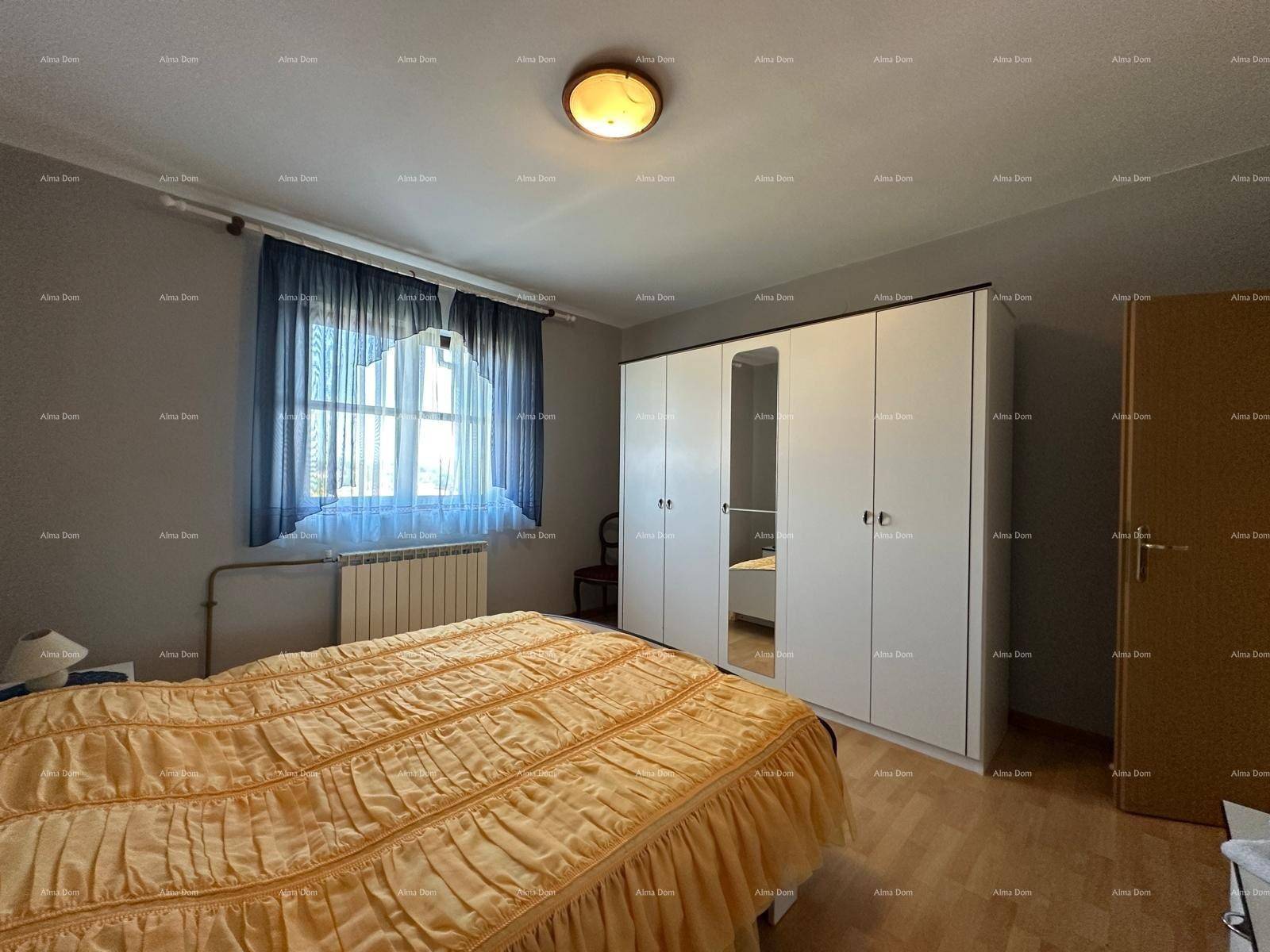 Schlafzimmer mit Doppelbett, weißem Kleiderschrank und Fenster mit blauen Vorhängen.