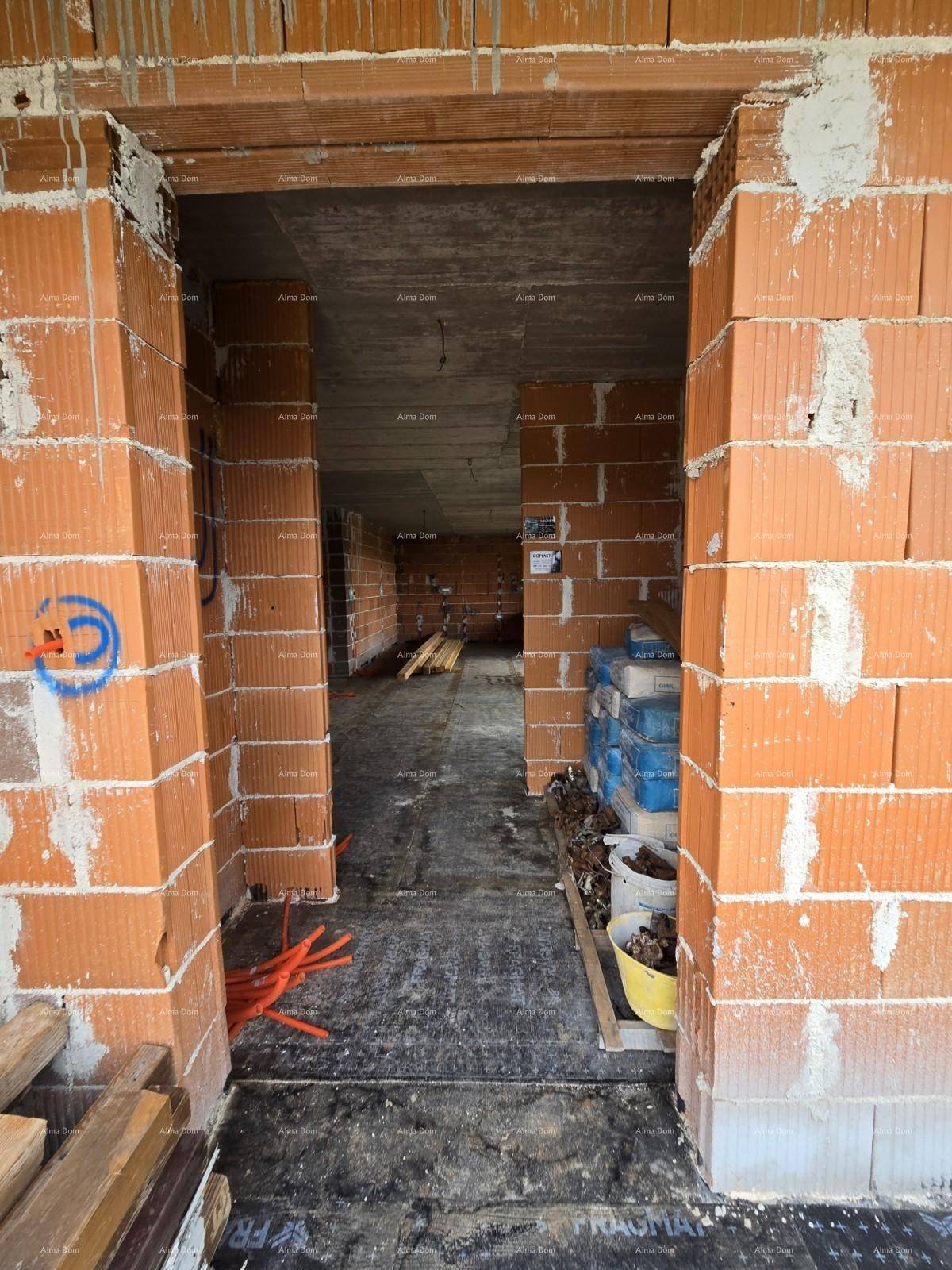 Blick durch eine Türöffnung in einen weiteren Raum im Rohbau mit Ziegelwänden und Betonboden.