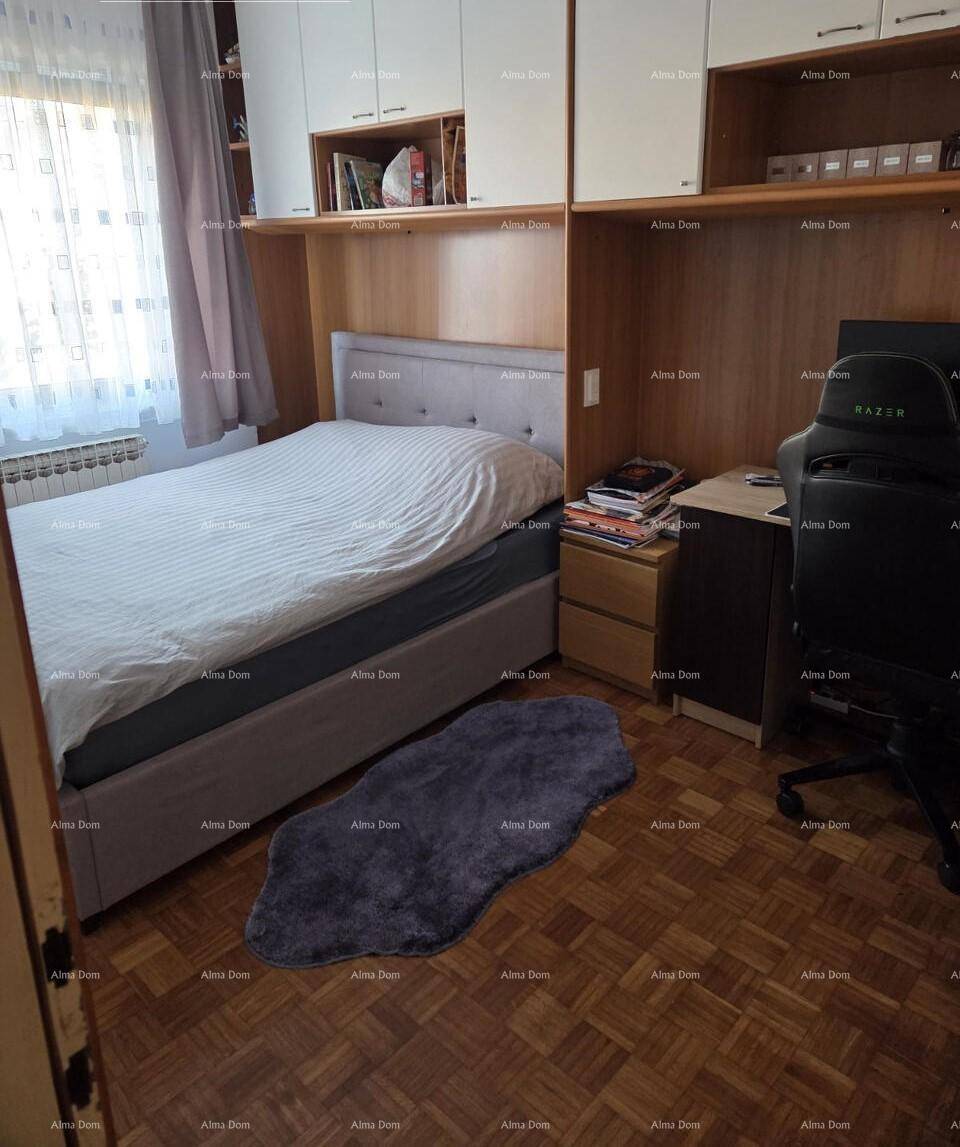 Schlafzimmer mit Einzelbett, Einbauschränken und einem Schreibtischbereich.