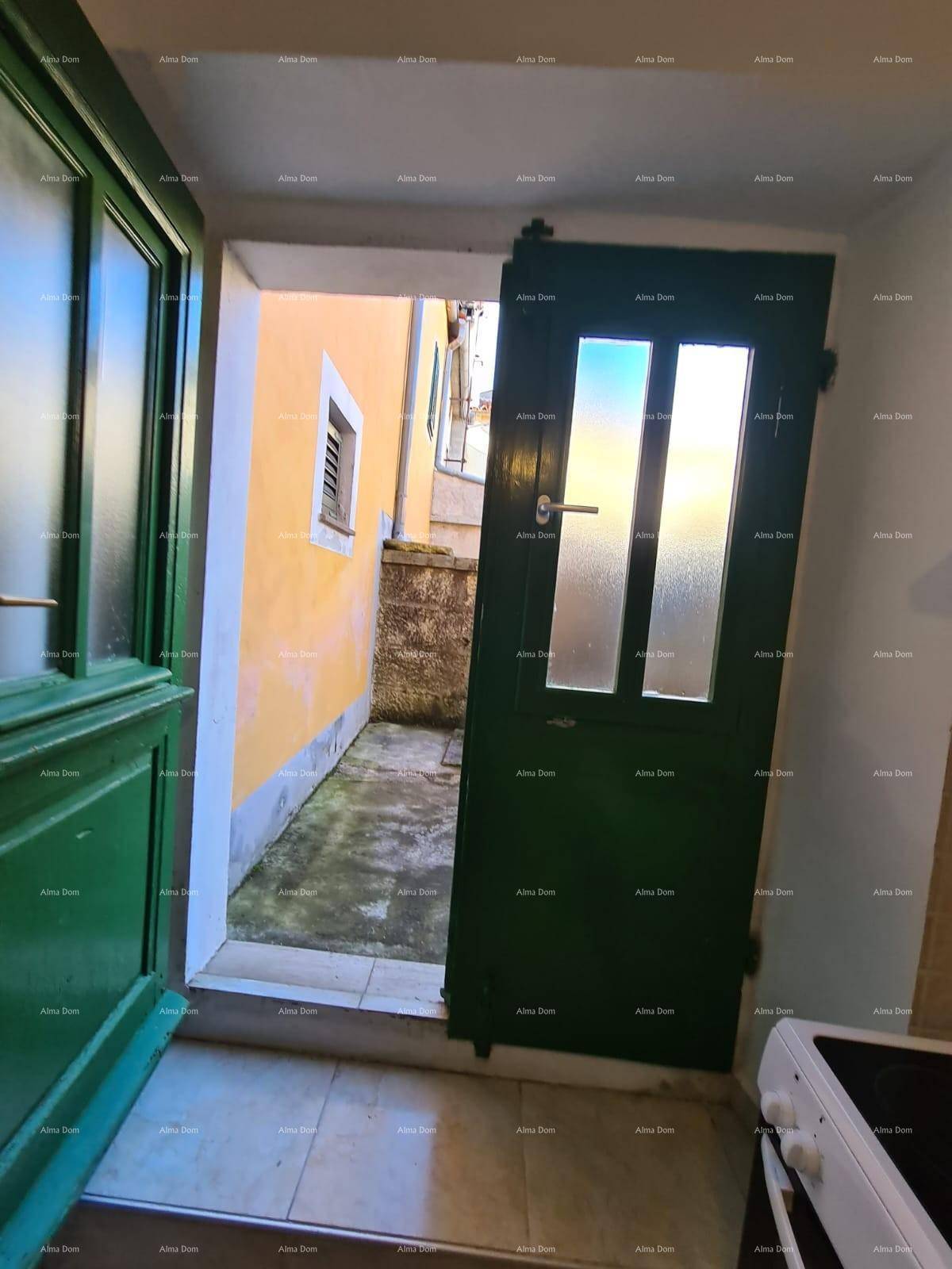 Offene grüne Tür führt zu einem kleinen, gepflasterten Innenhof.