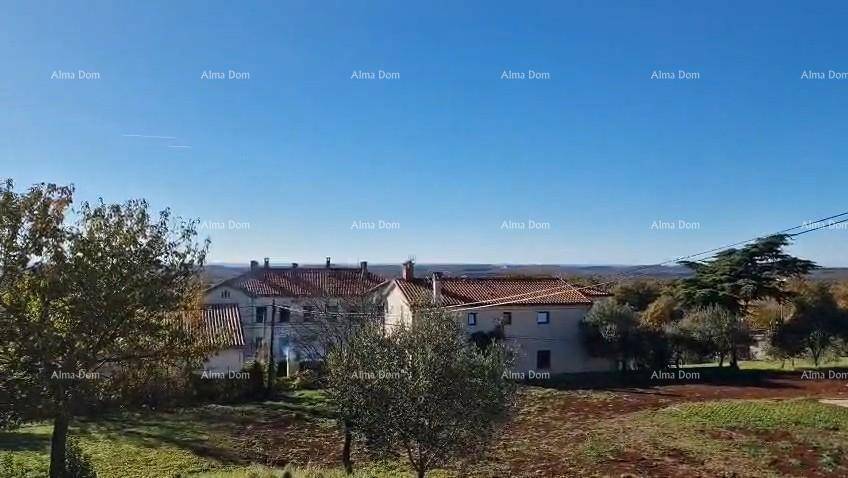Weitläufige Landschaft mit traditionellen Häusern und Bäumen unter einem klaren blauen Himmel.