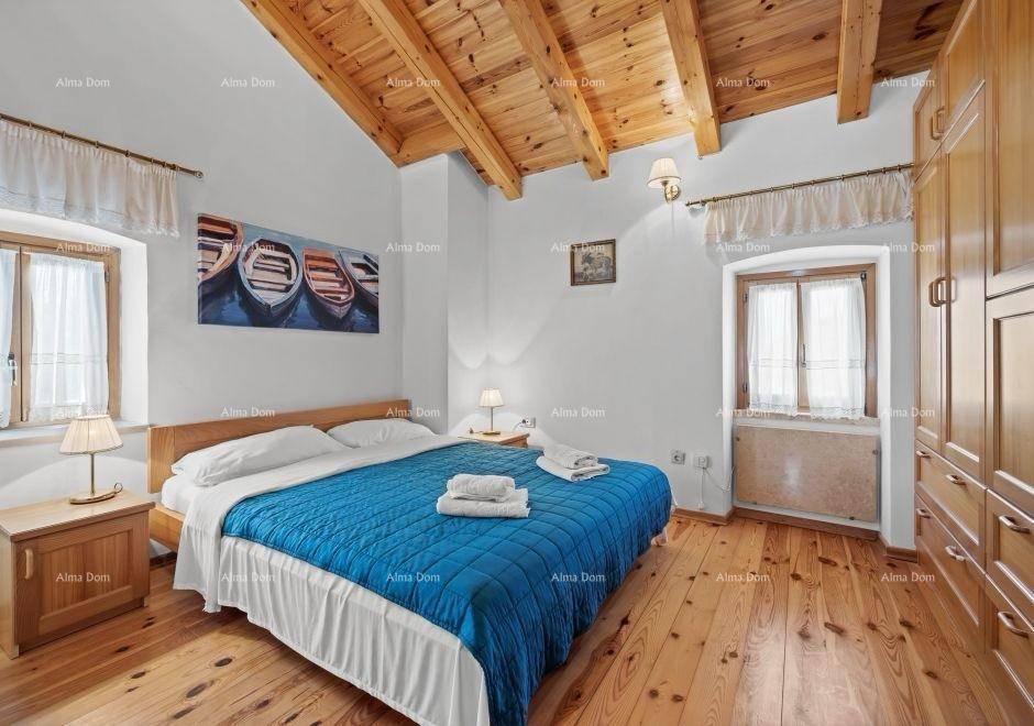 Schlafzimmer mit Doppelbett, Holzboden, sichtbaren Dachbalken und blauer Bettdecke.
