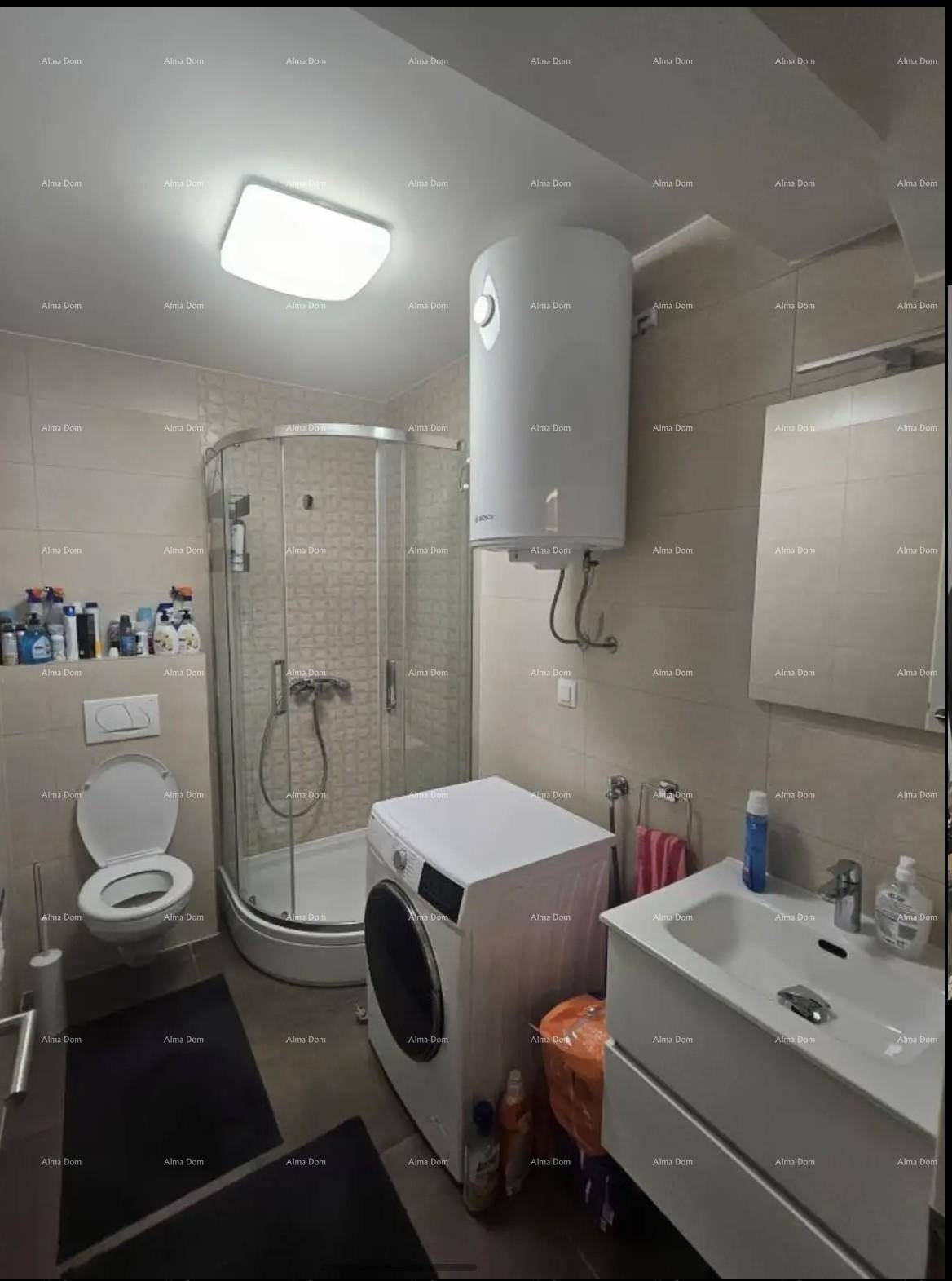 Funktionales Badezimmer mit Duschkabine, WC, Waschmaschine und Wandboiler in hellen Fliesen.