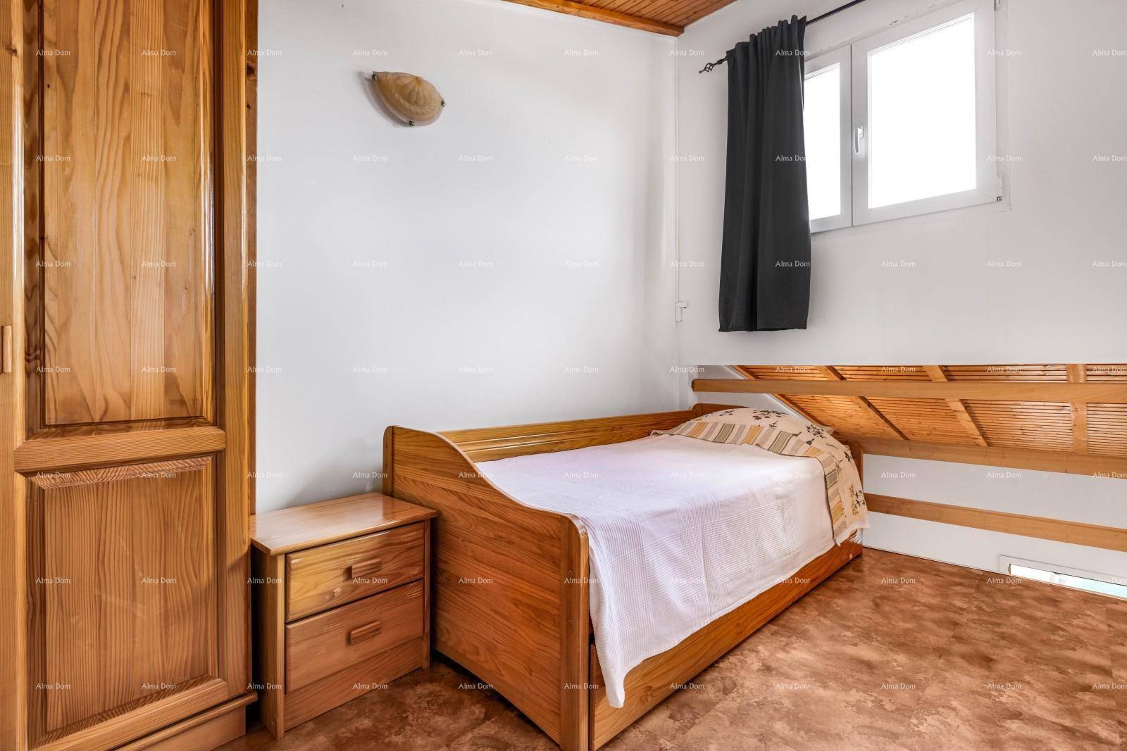 Gemütliches Schlafzimmer mit Einzelbett, Holzmöbeln und Fenster mit Vorhang.