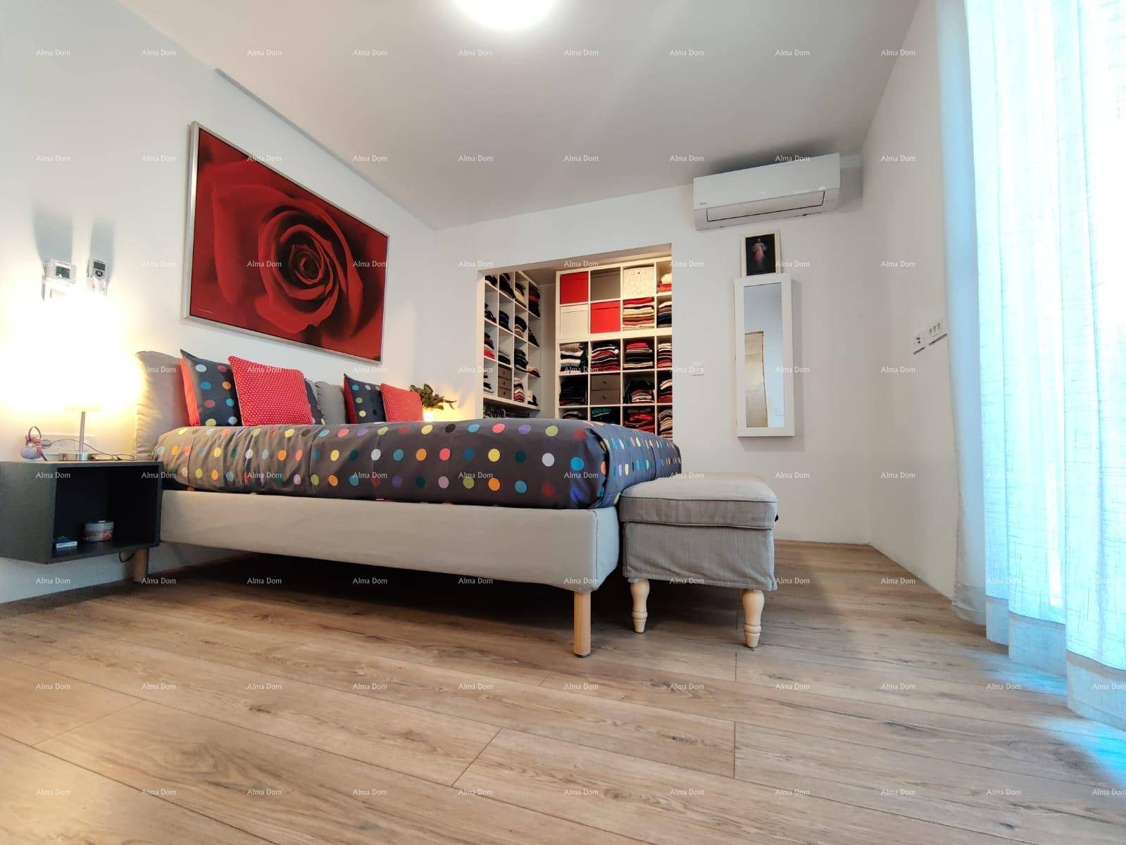 Schlafzimmer mit Holzboden, großem Bett und offenem Zugang zu einem begehbaren Kleiderschrank.