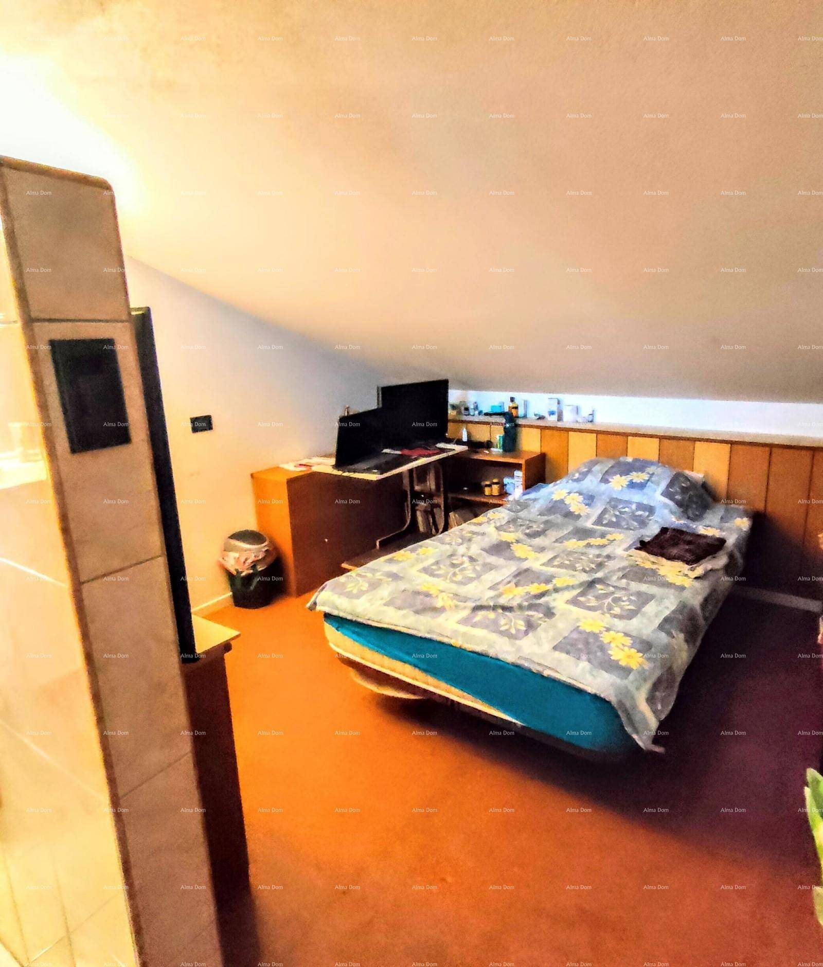 Dachschlafzimmer mit schrägen Wänden, Teppichboden und einem kleinen Arbeitsbereich unter dem Dach.
