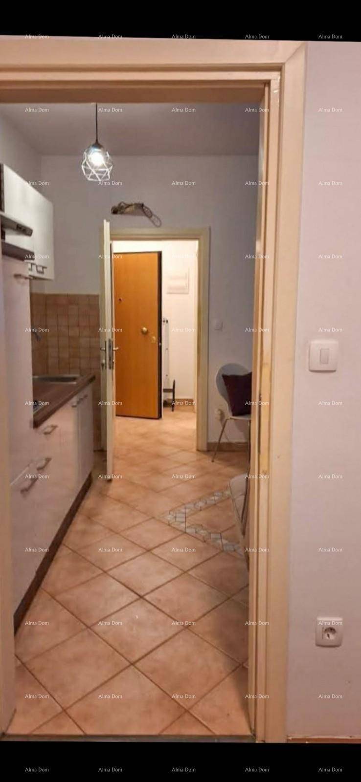 Blick von einem gefliesten Bereich mit Küchenzeile in einen Flur mit geschlossener Holztür.